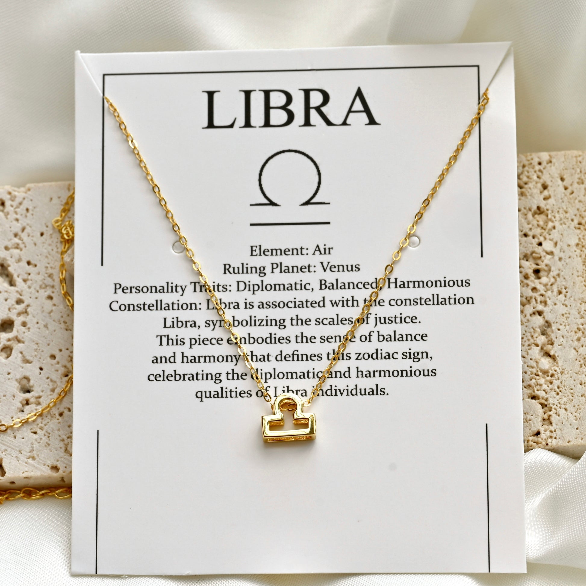 Gold necklace on a card with Libra zodiac information