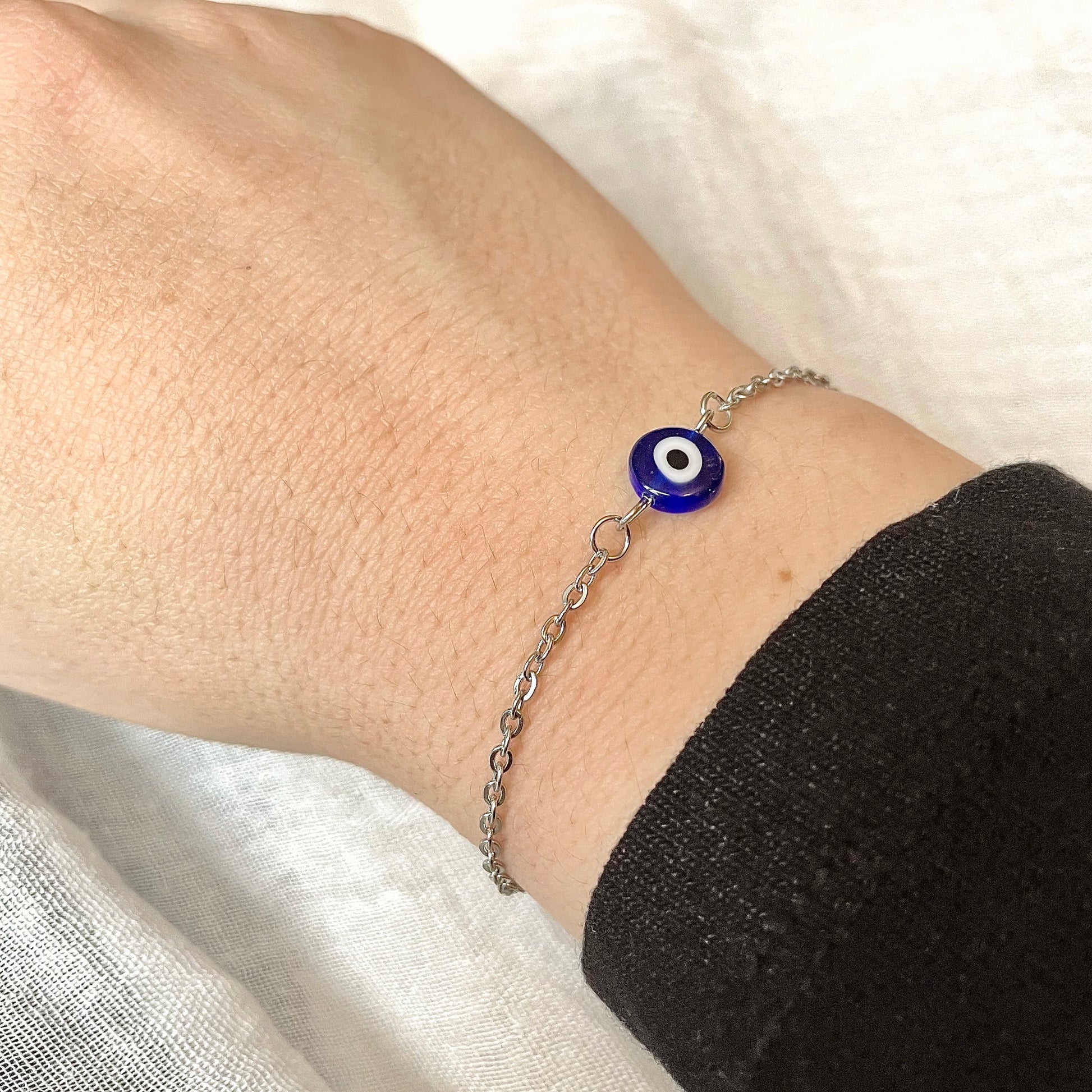Silver evil eye bracelet worn on a wrist against a white background