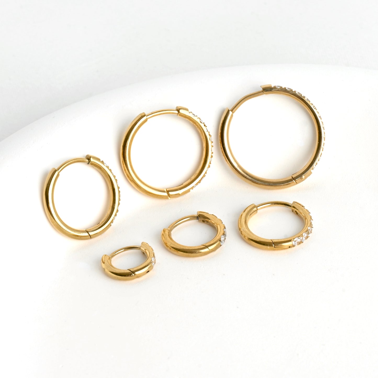 Set of gold hoop earrings on a white background