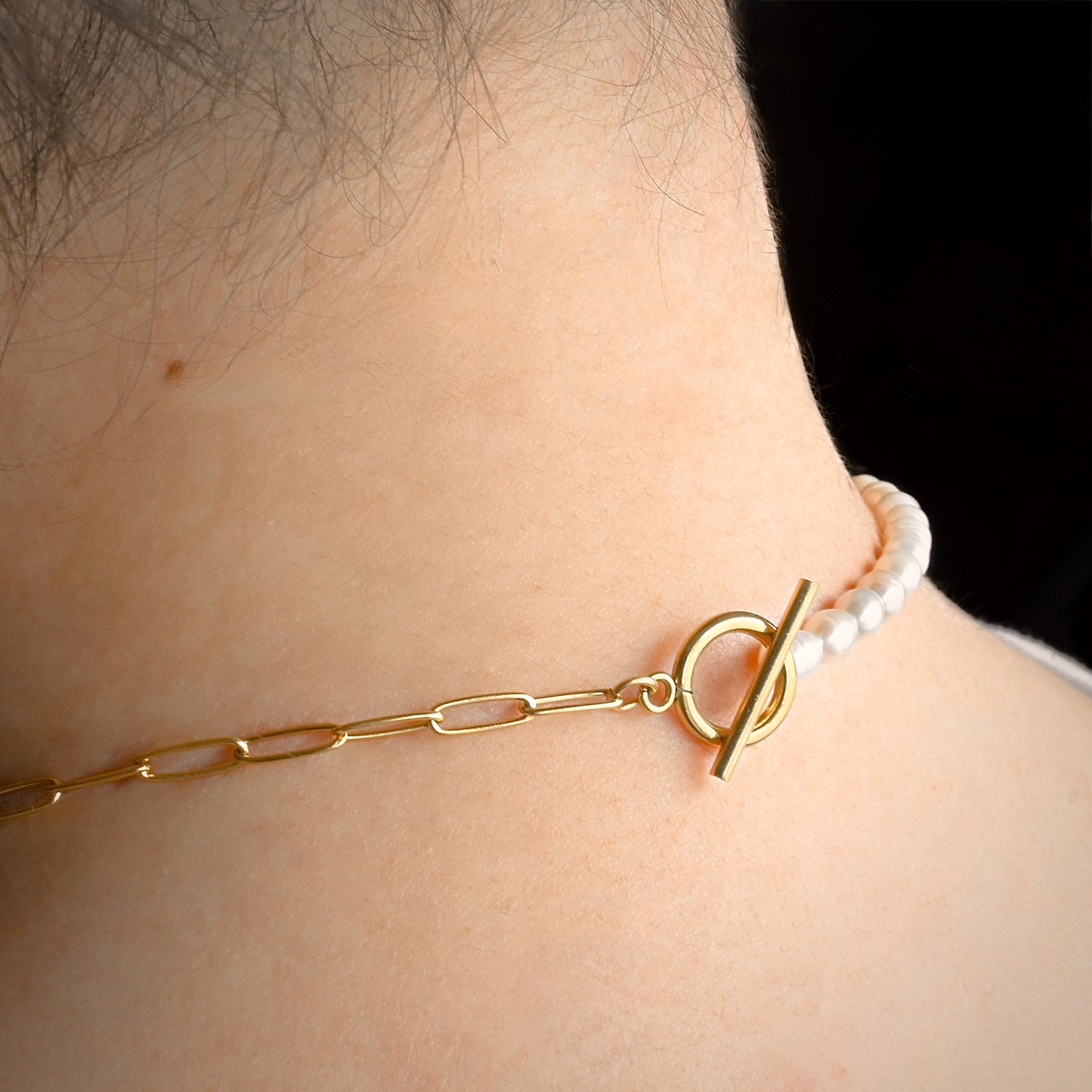 Gold necklace with a toggle clasp worn around the neck