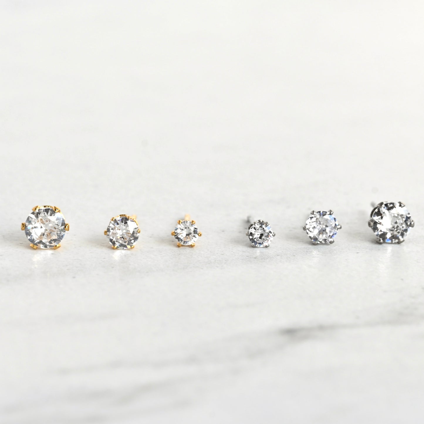 Front view of gold and silver diamond stud earrings with six-prong basket setting