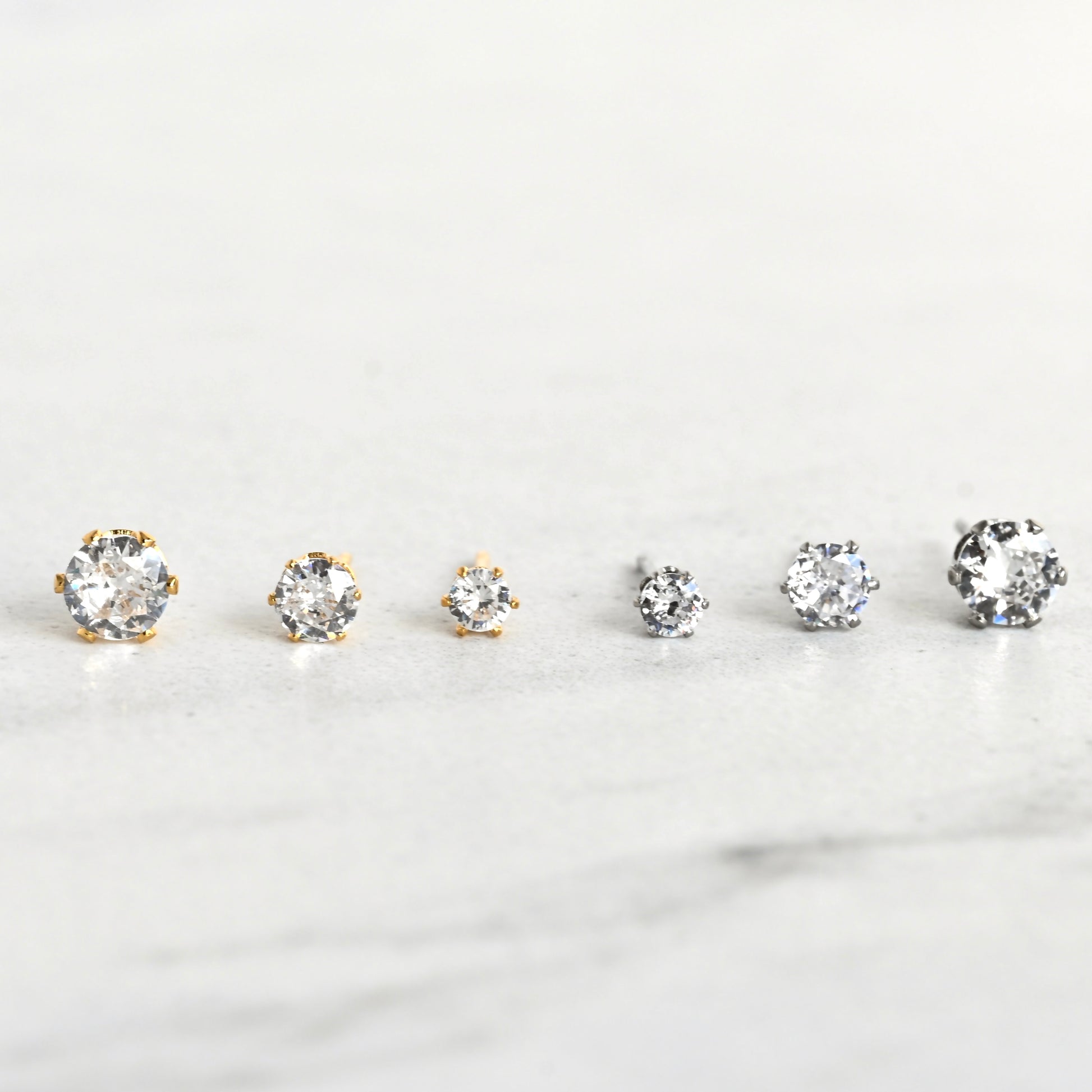 Front view of gold and silver diamond stud earrings with six-prong basket setting
