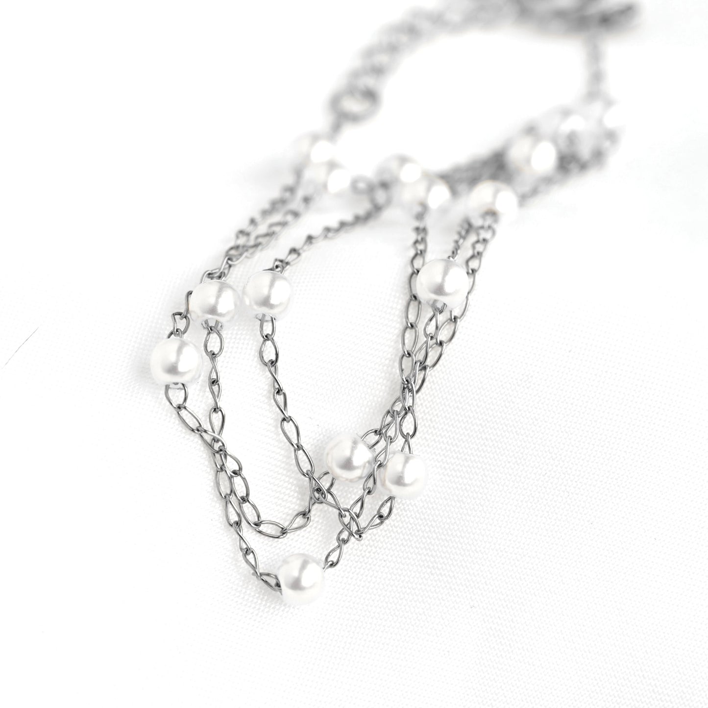 Silver chain necklace with pearls on a white background