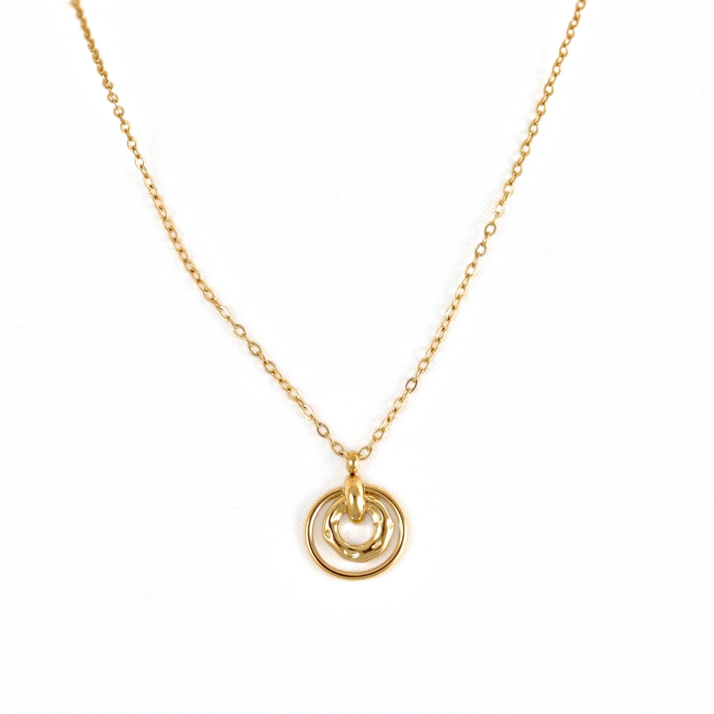 A delicate gold chain necklace featuring a pendant with two interlocking circular rings, one of which has a small heart-shaped cutout, shown against a plain white background.