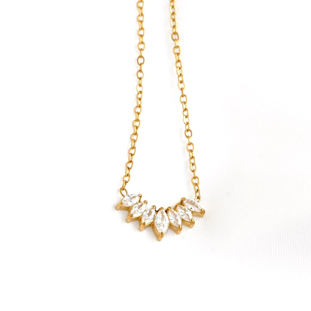 A delicate gold chain necklace featuring a small, curved cluster of marquise-cut clear crystals in a gold setting, displayed against a clean white background.