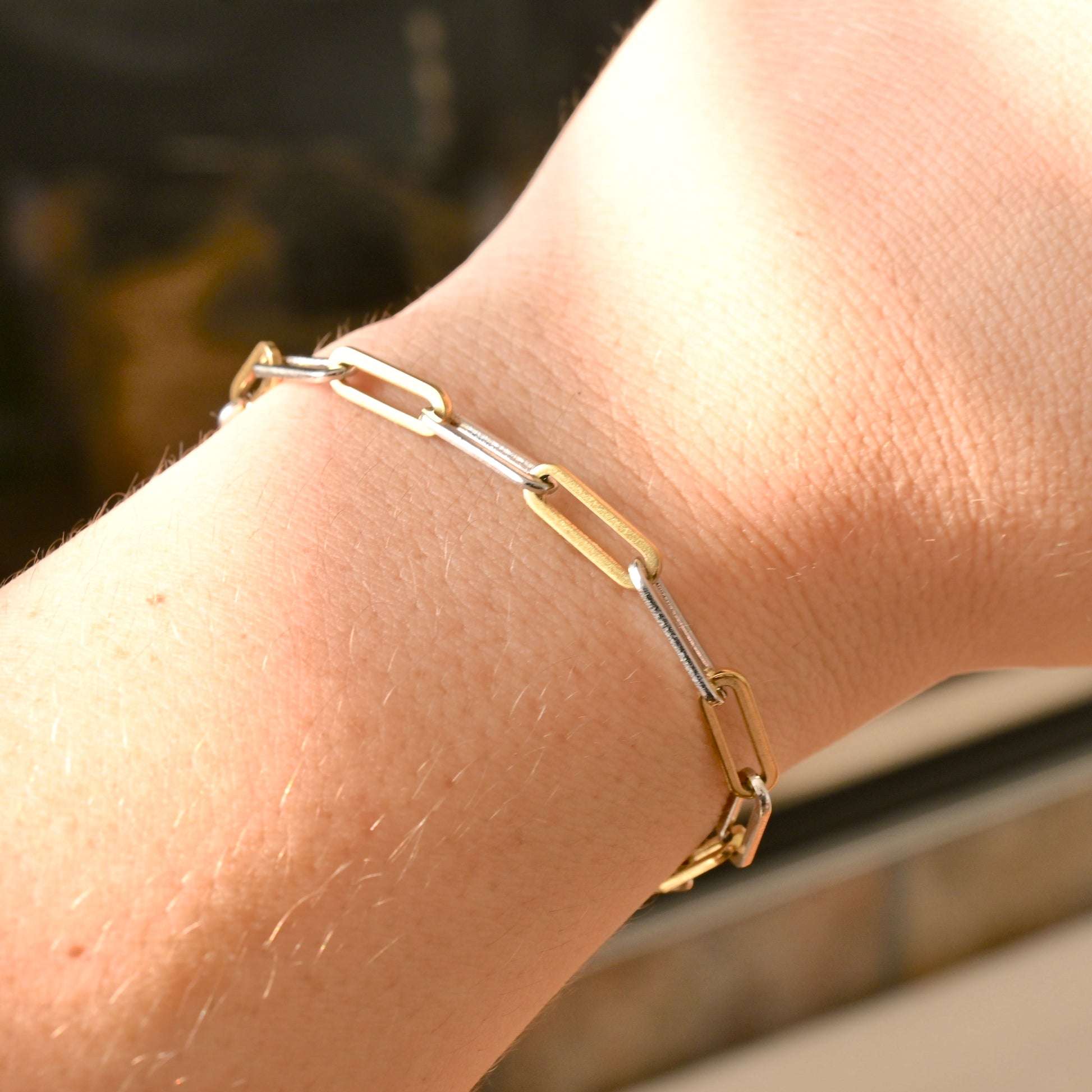 mized metal paperclip bracelet on a wrist with a blurred background