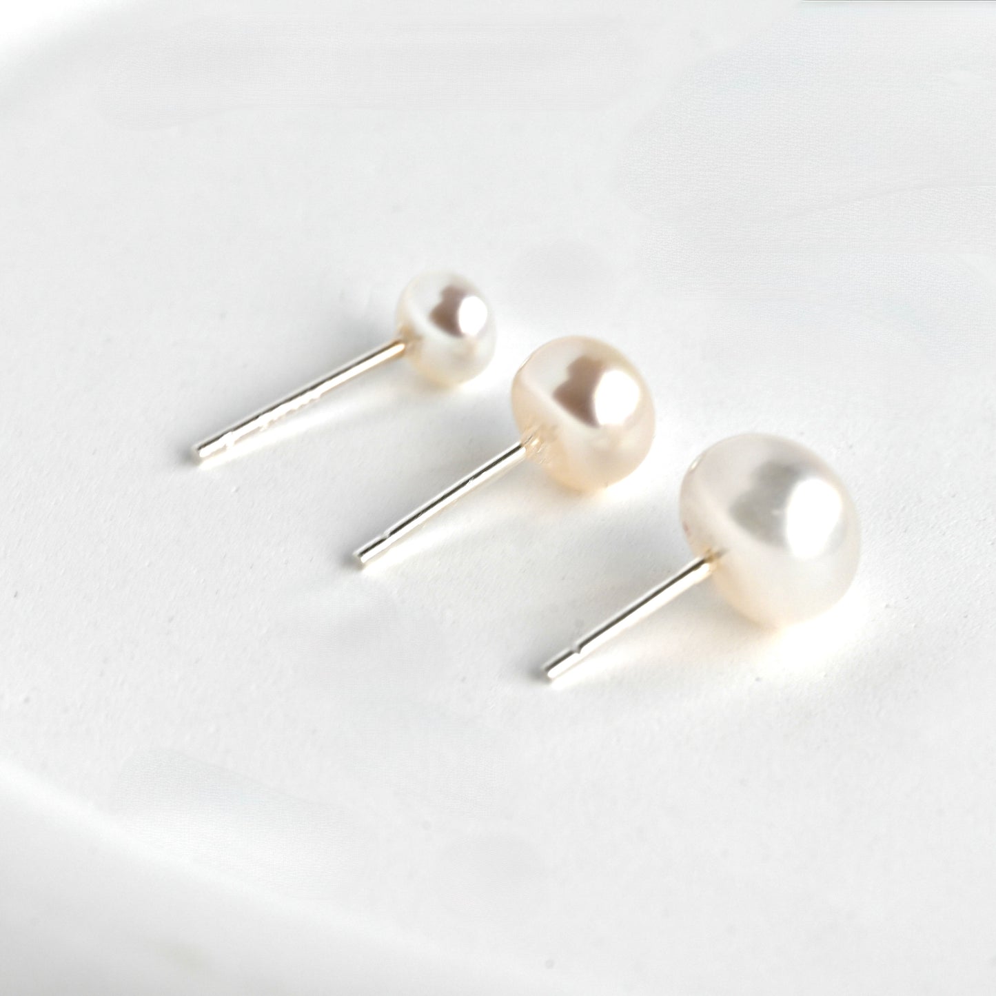Round pearl stud earrings on a white background