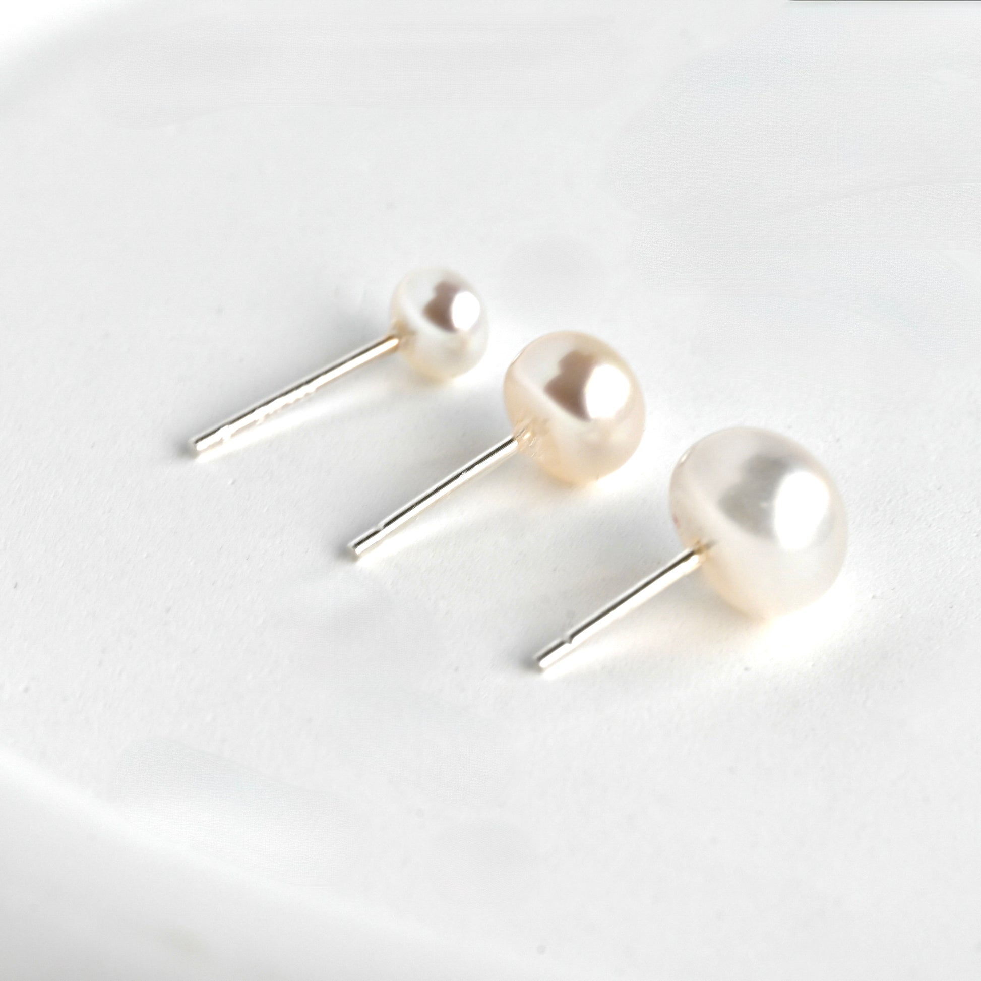 Round pearl stud earrings on a white background