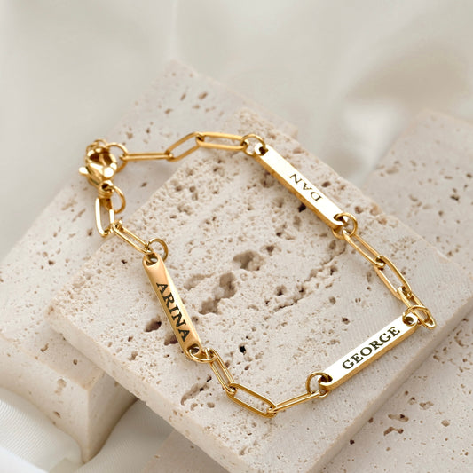 Gold bracelet with engraved names on a textured stone surface