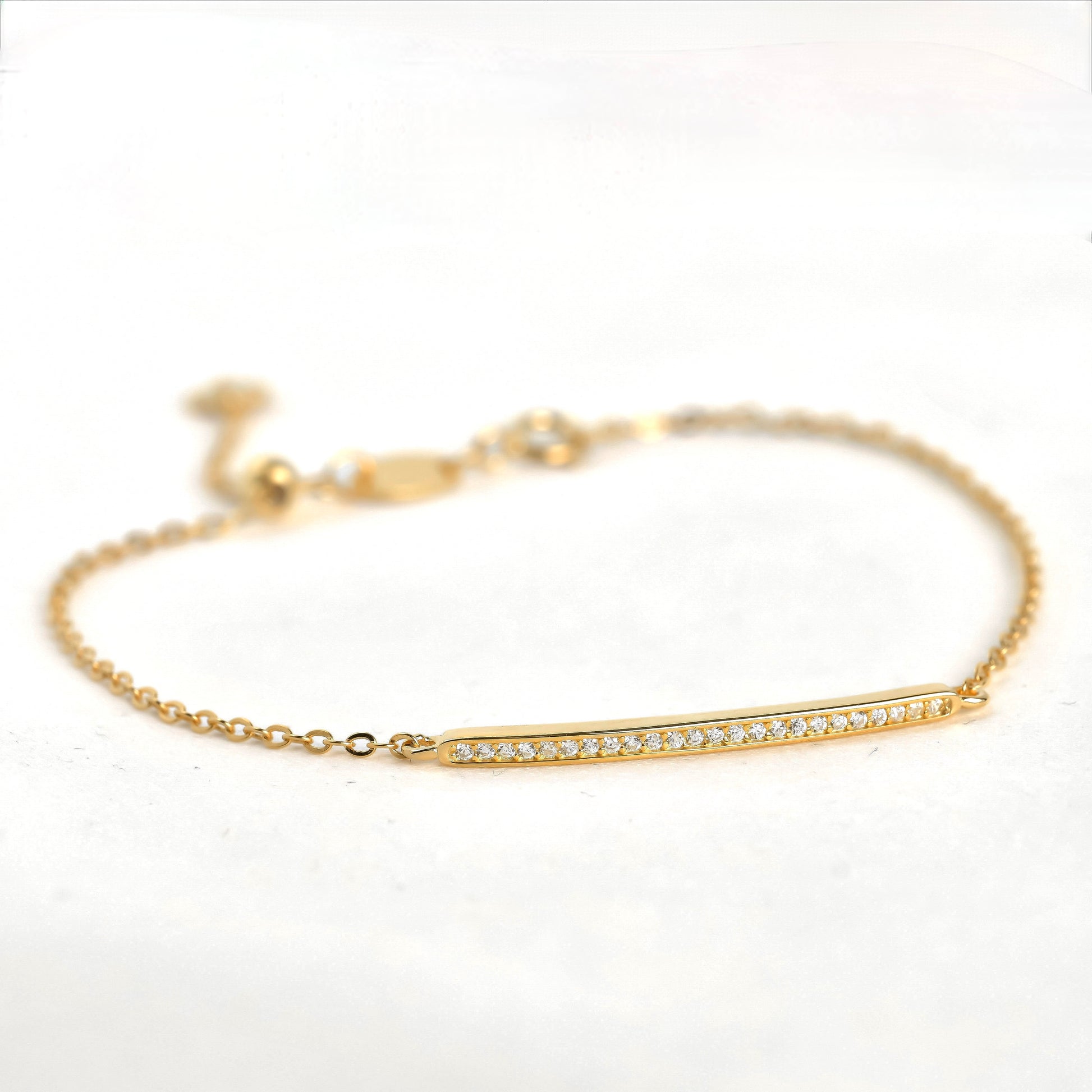 Gold bracelet with a thin pave CZ bar on a white background