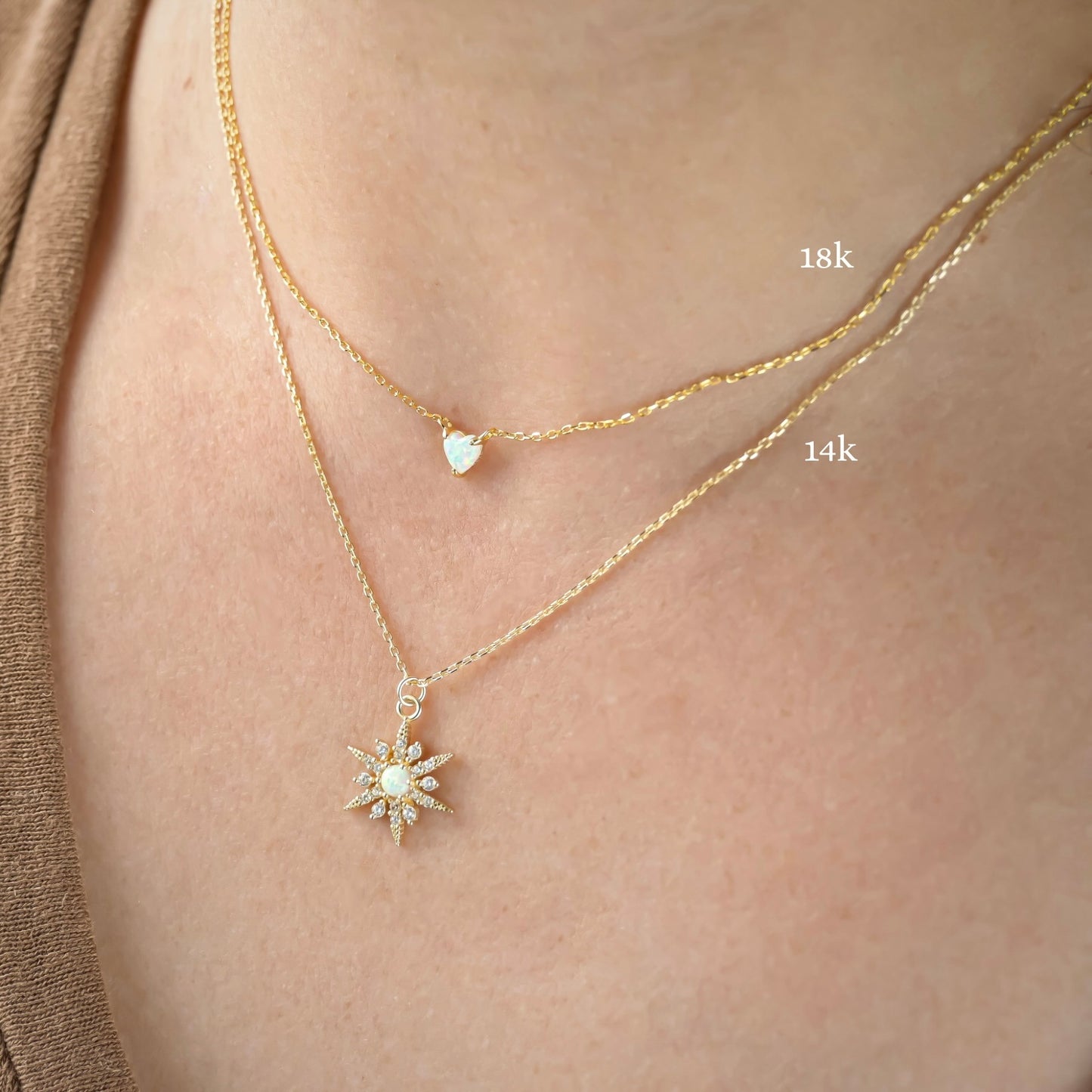 Two gold necklaces with pendants on a person's neck, heart one labeled '18k' and star necklace '14k'.