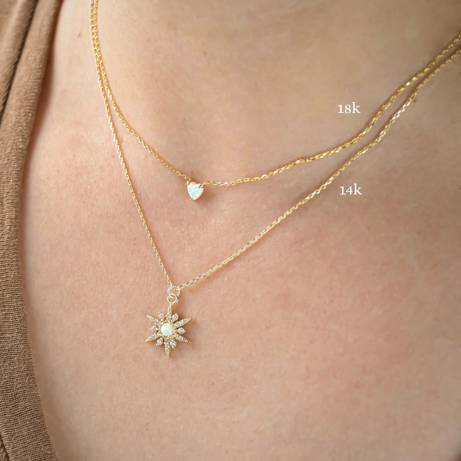 Two gold necklaces with pendants on a person's neck, heart one labeled '18k' and star necklace '14k'.