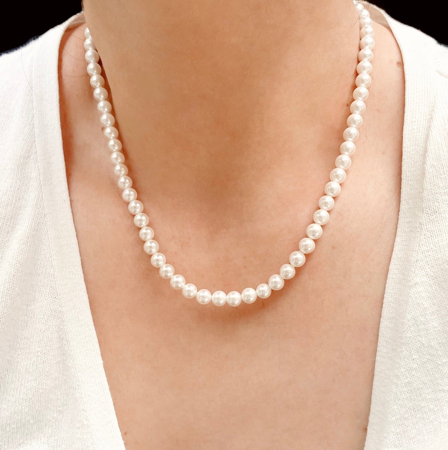 Round shell pearl necklace in 18 inches being worn on a person with a plain background