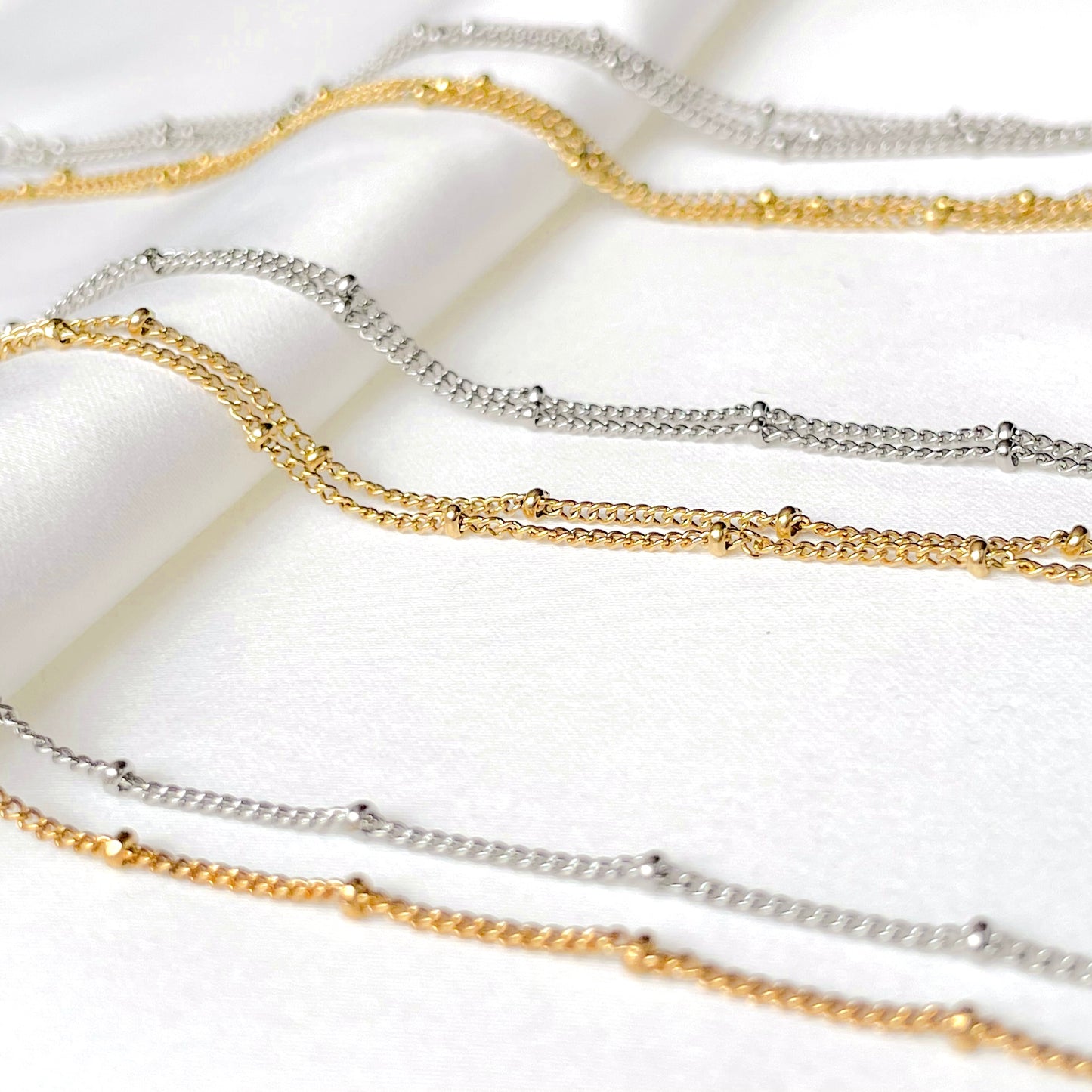 One, two and three-layered bracelets in gold and silver on a white background