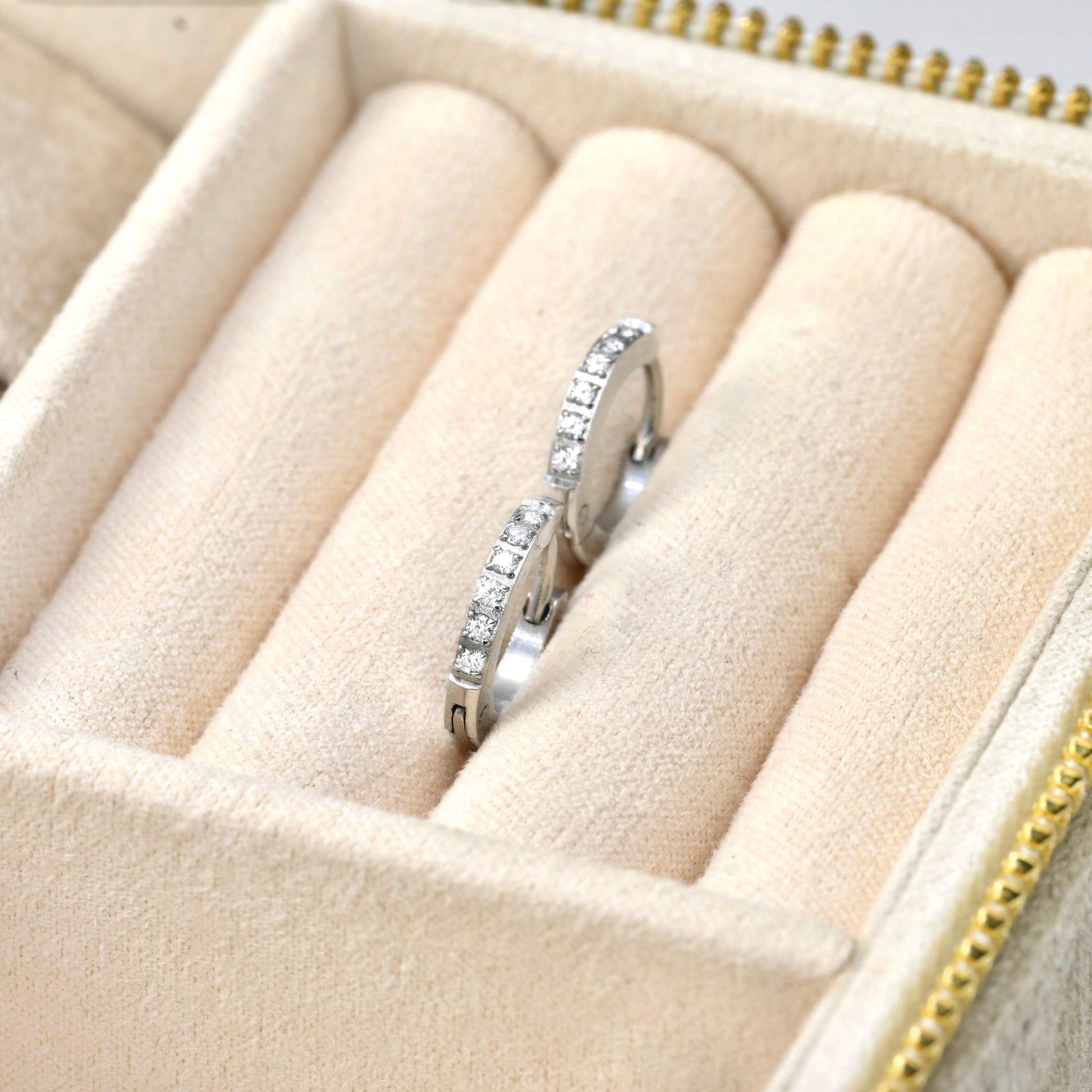Silver clicker earrings with diamonds in a beige jewelry box