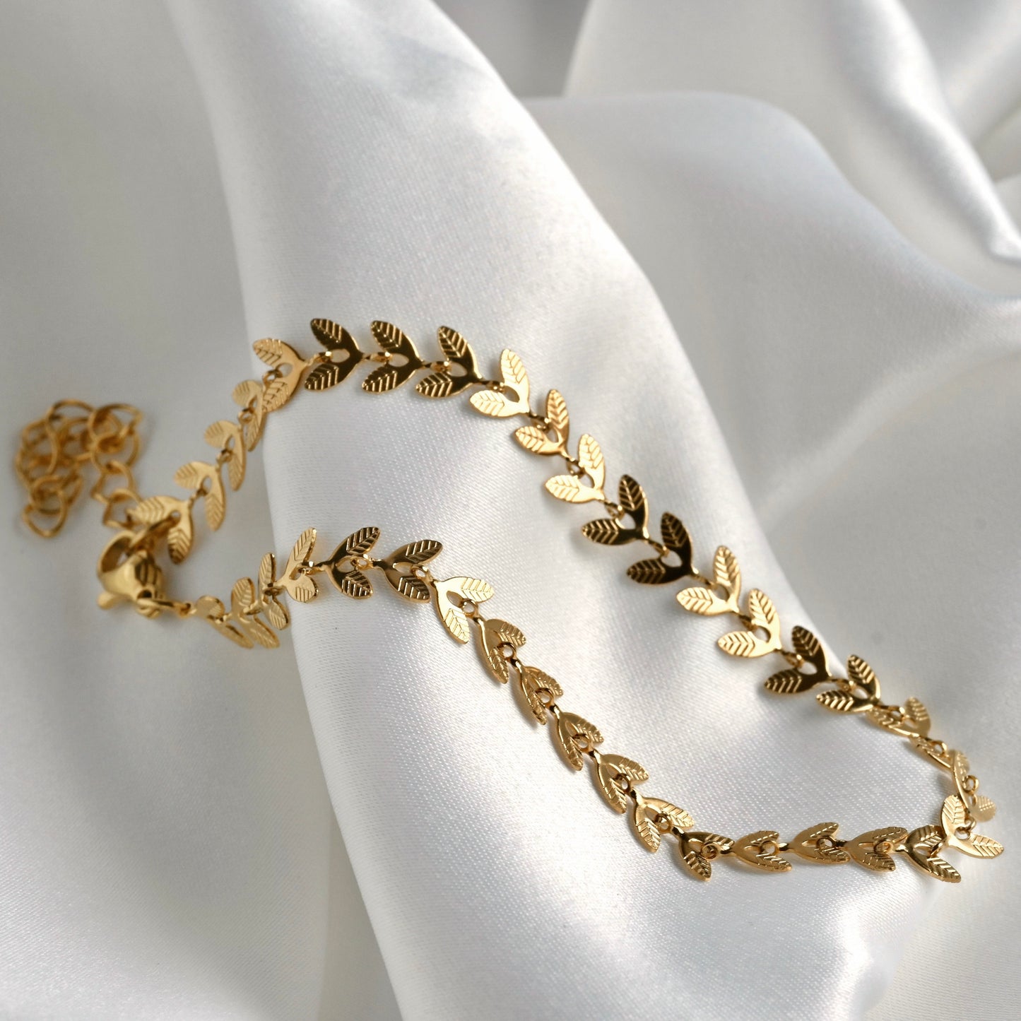 Gold leaf bracelet on a white fabric background