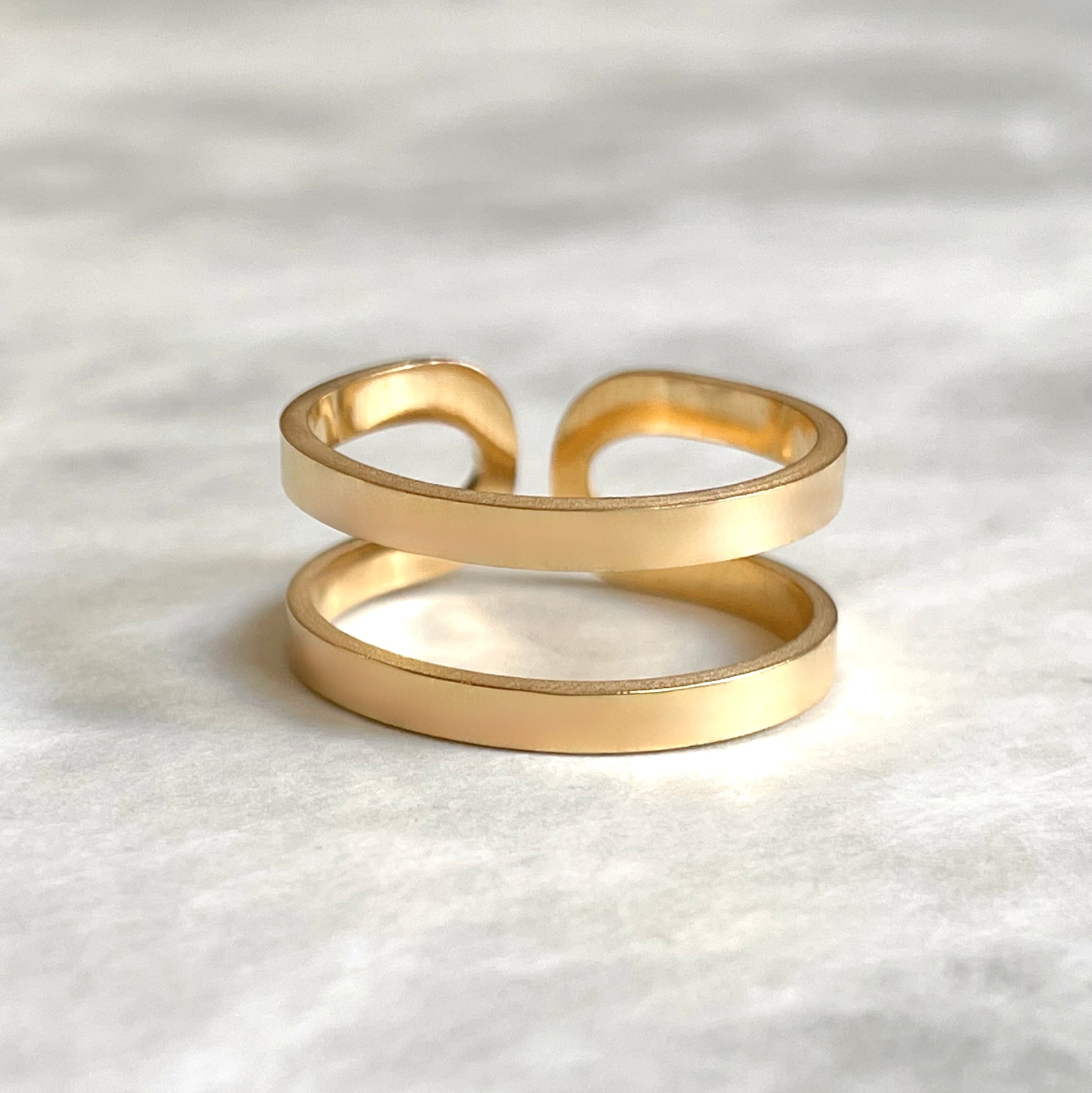 Front view of bold adjustable ring in gold on a textured white surface