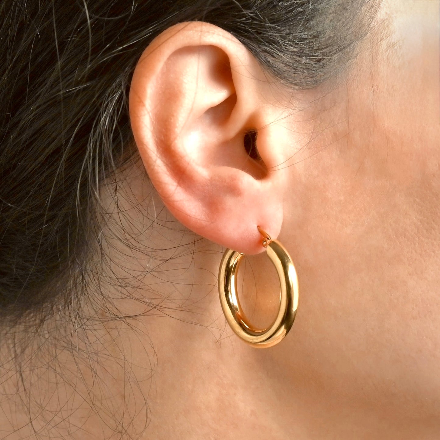 Side view of a person wearing 30 mm chunky gold hoops 