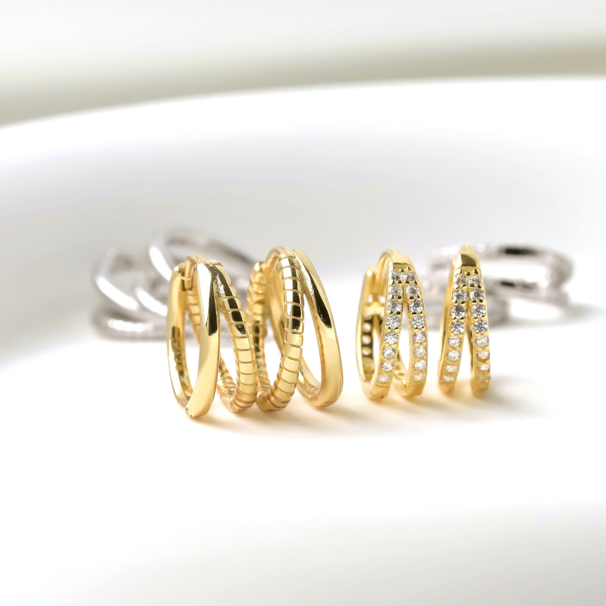 Set of gold and silver huggie hoop earrings on a white background
