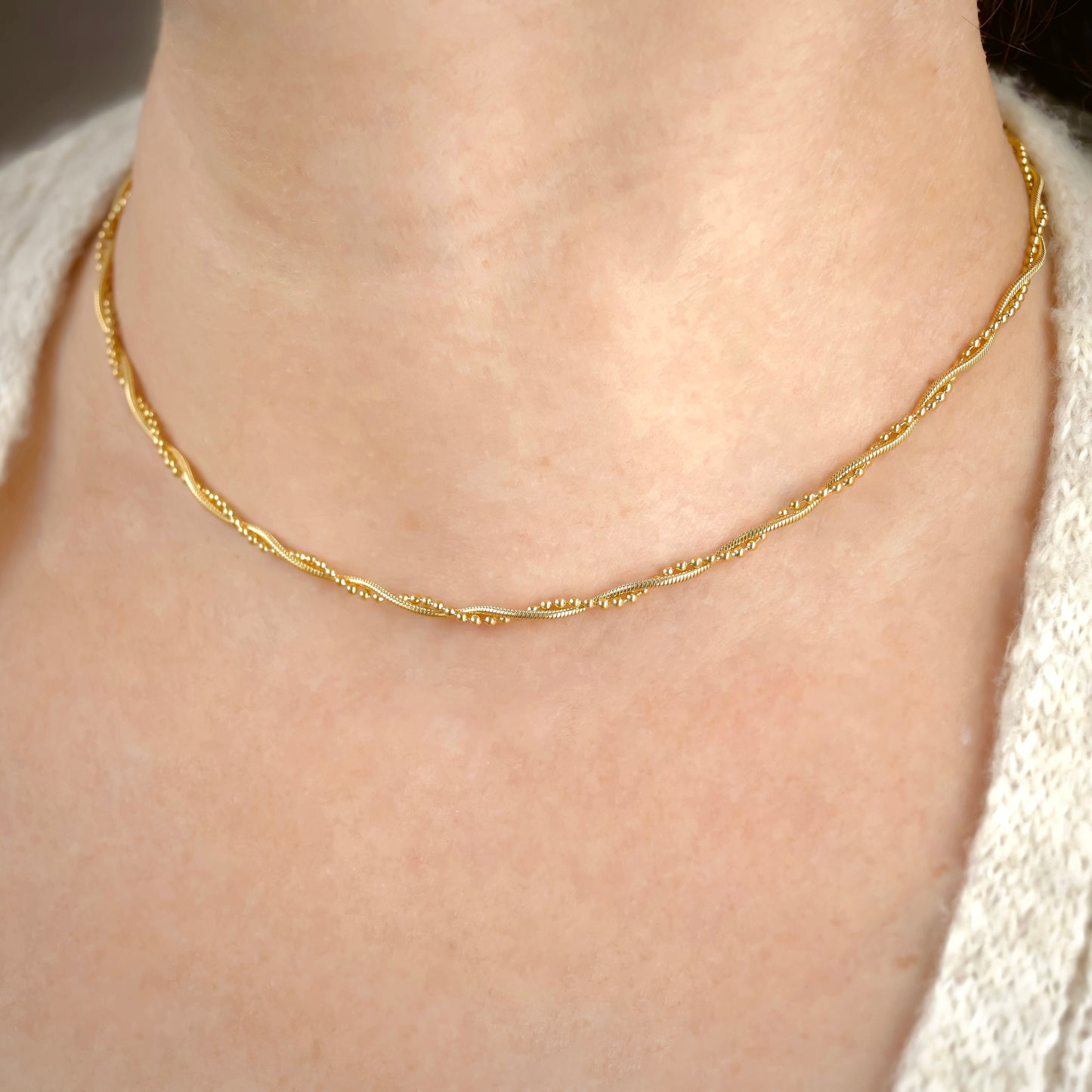 Layered Gold snake necklace on a person's neck with a neutral background