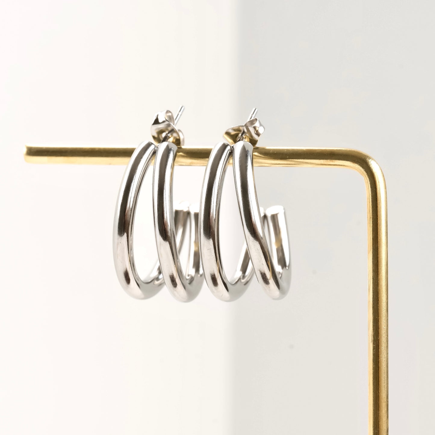 Medium Silver hoop earrings on a gold stand against a white background