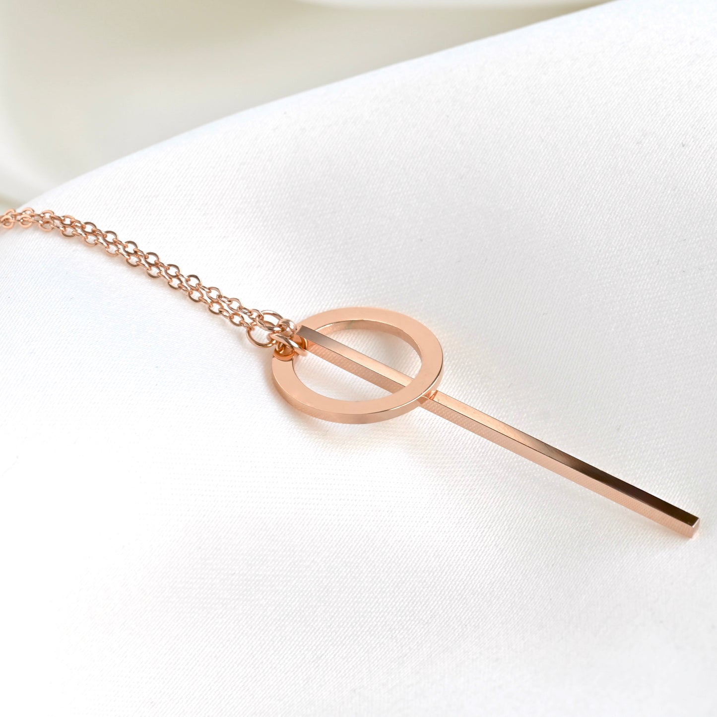 Close-up view of rose gold necklace with a circle and long thin bar through the circle