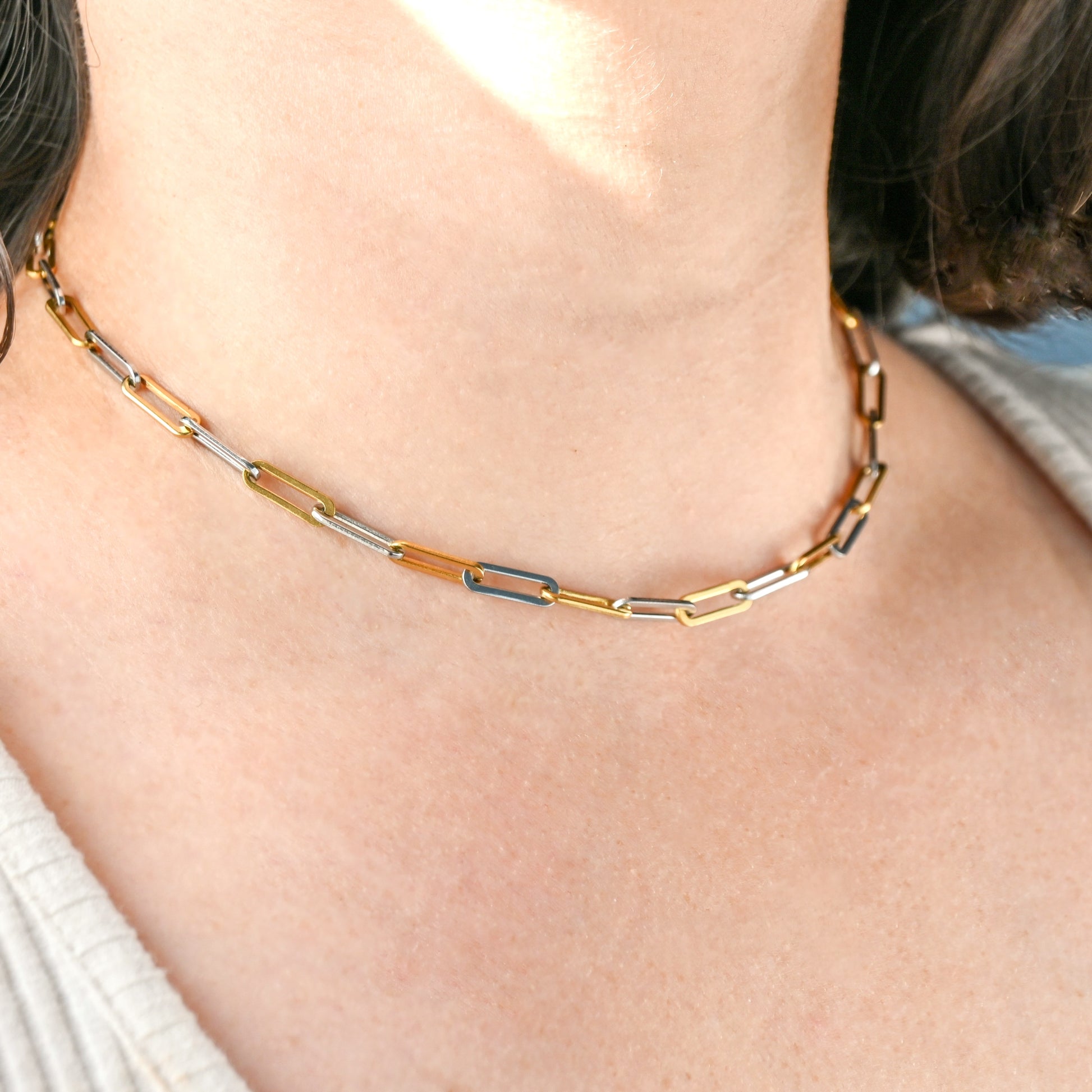 Close-up of a person wearing a gold and silver paperclip necklace.