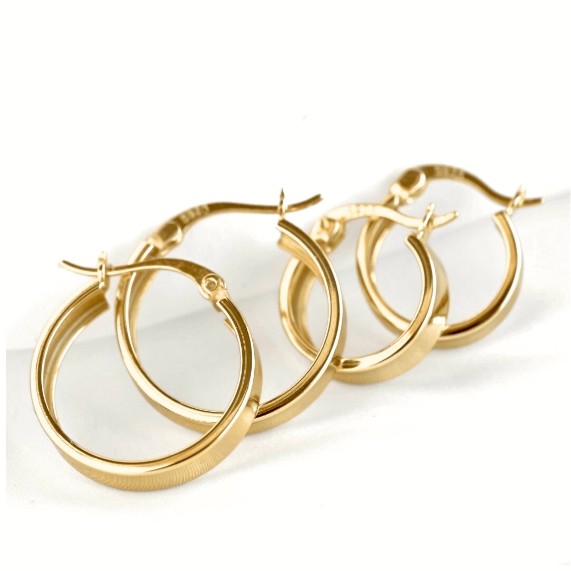 A pair of polished gold hoop earrings with a textured inner band and secure latch back clasp, displayed on a clean white background.