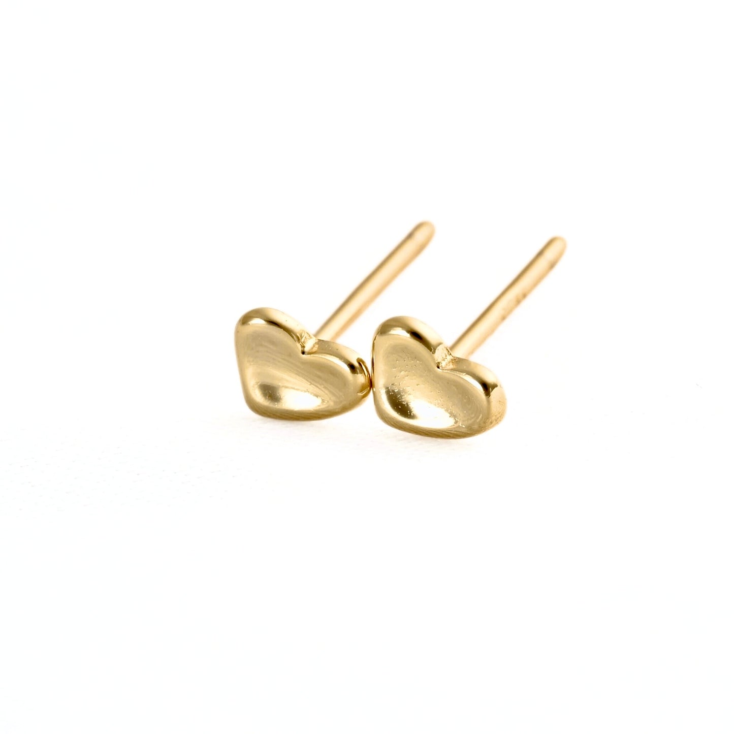 A pair of small gold heart stud earrings with post backs, shown on a clean white background.