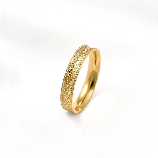 Gold milgrain ring with a slightly curved design and honeycomb interior displayed on white surface.