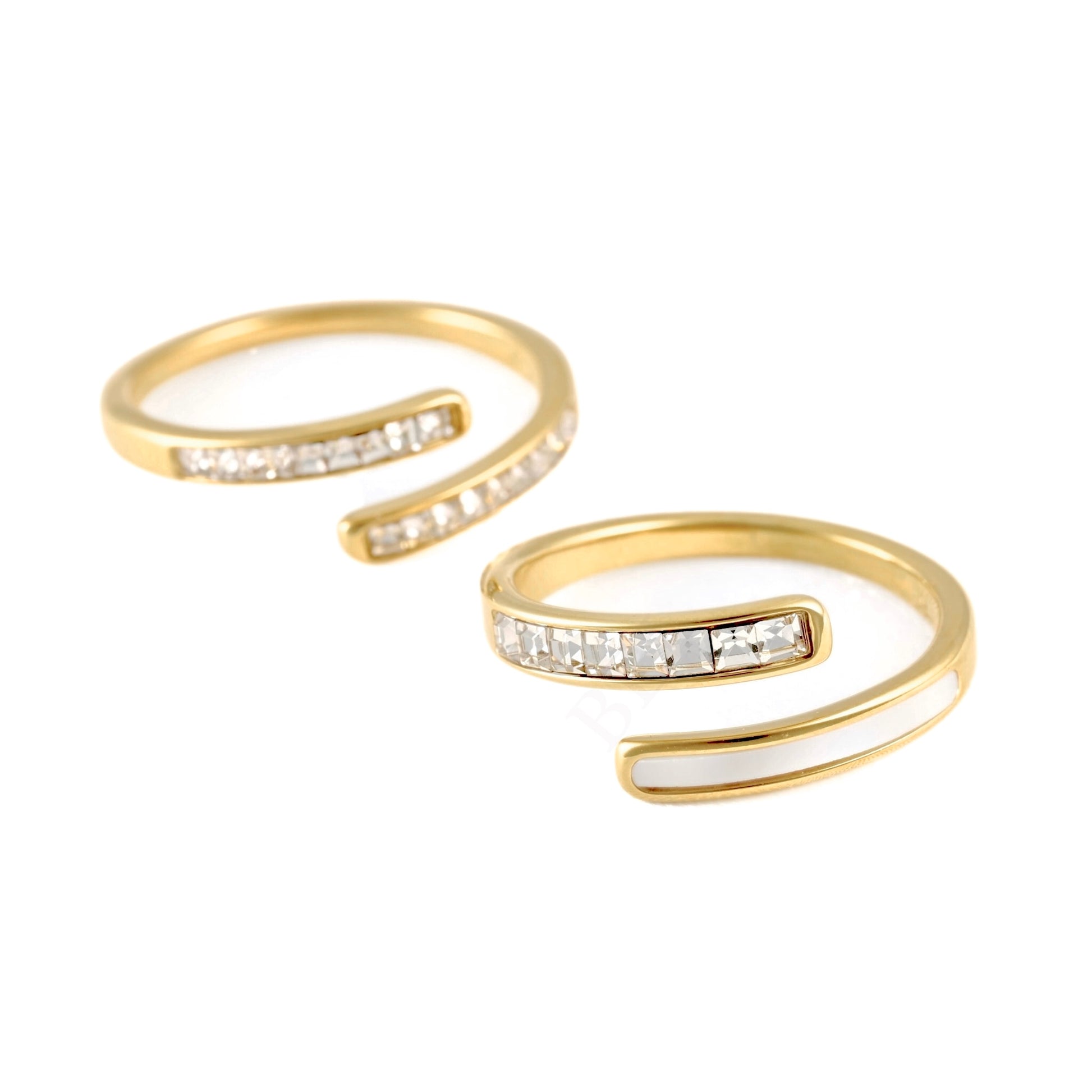 A pair of gold open wrap rings, each featuring a channel-set row of clear rectangular gemstones on the front, displayed on a clean white background.
