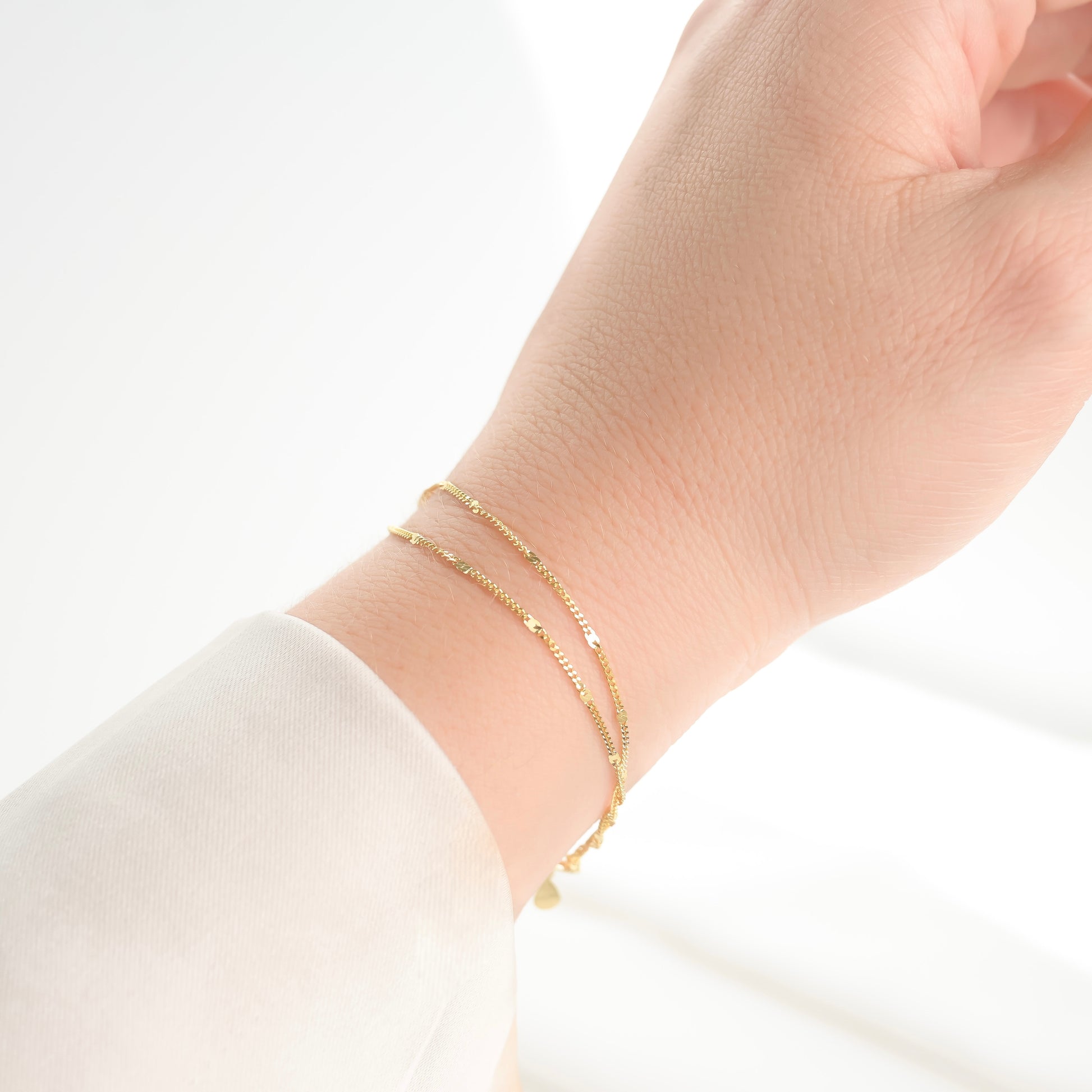 Gold bracelet on a person's wrist against a white background