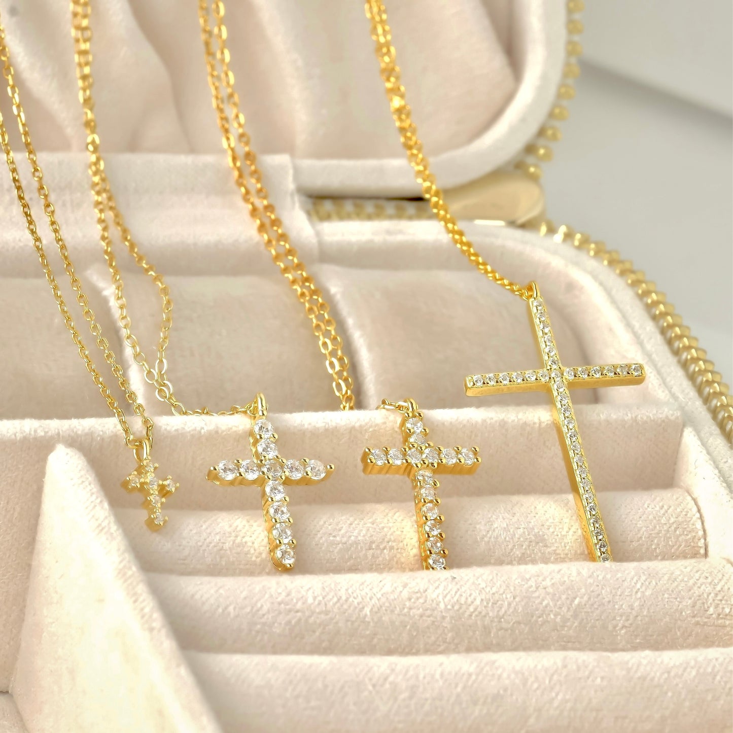 Collection of gold cross necklaces on a soft beige surface