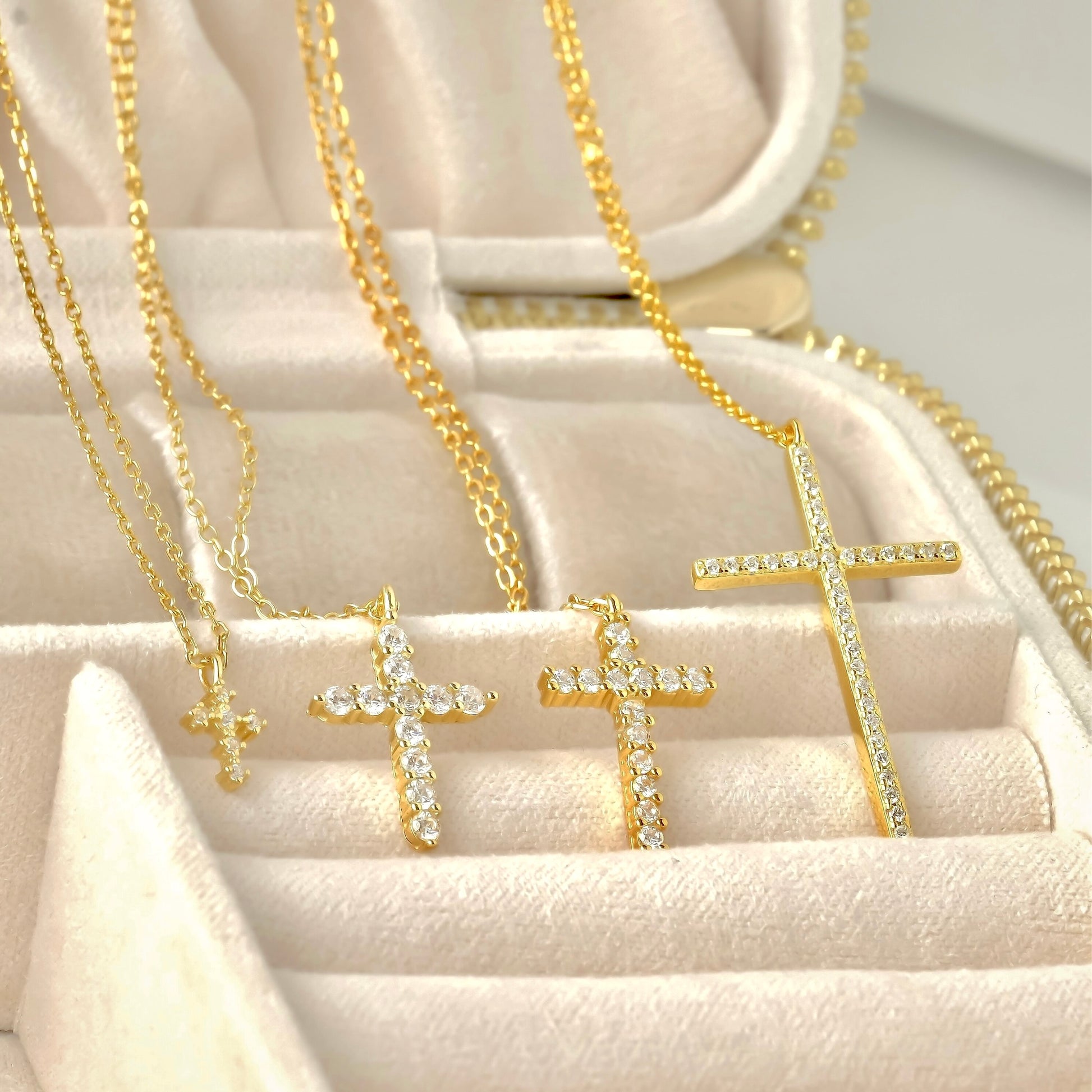 Collection of gold cross necklaces on a soft beige surface