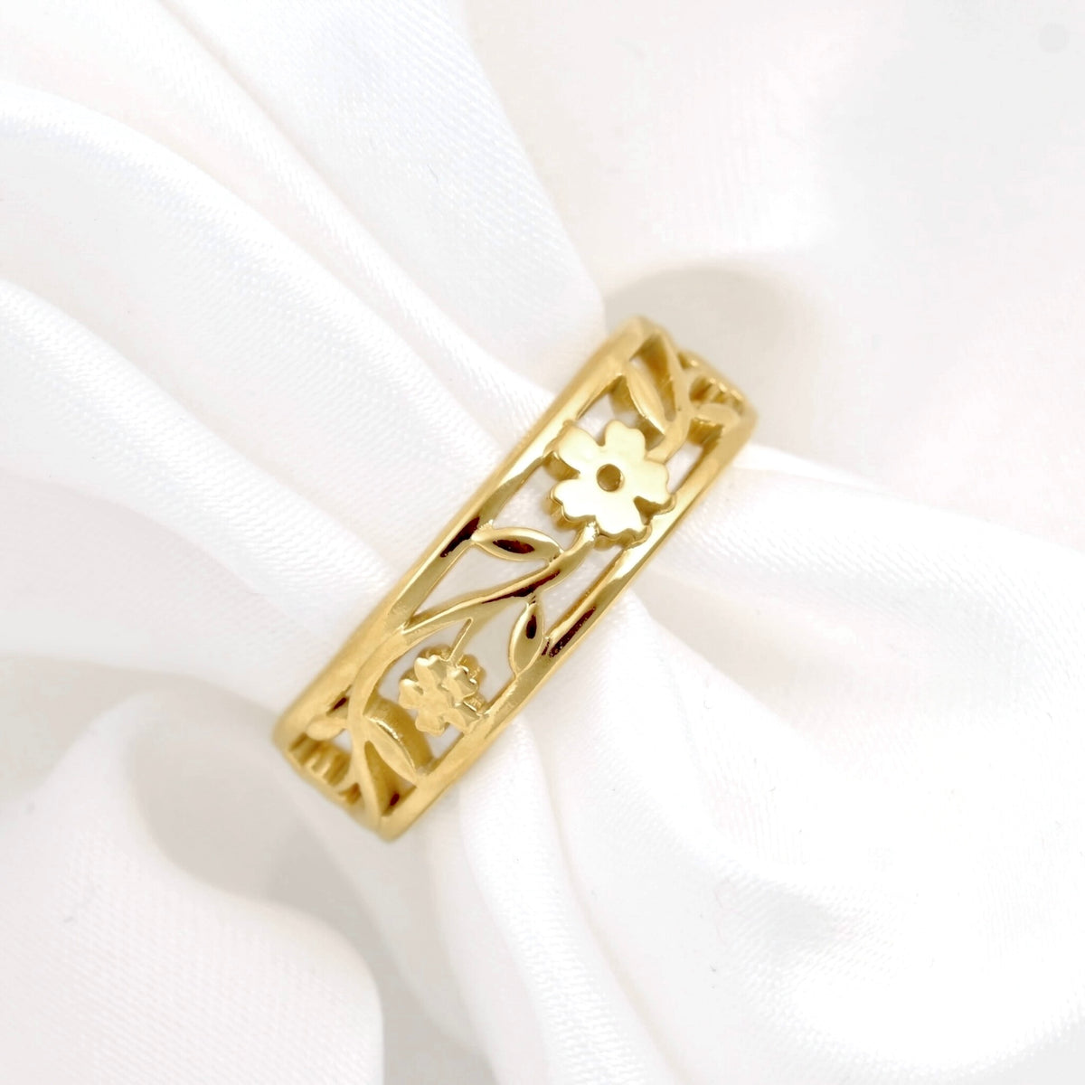 Minimalist gold ring on white satin ribbon, with cut-out flower and leaf design.