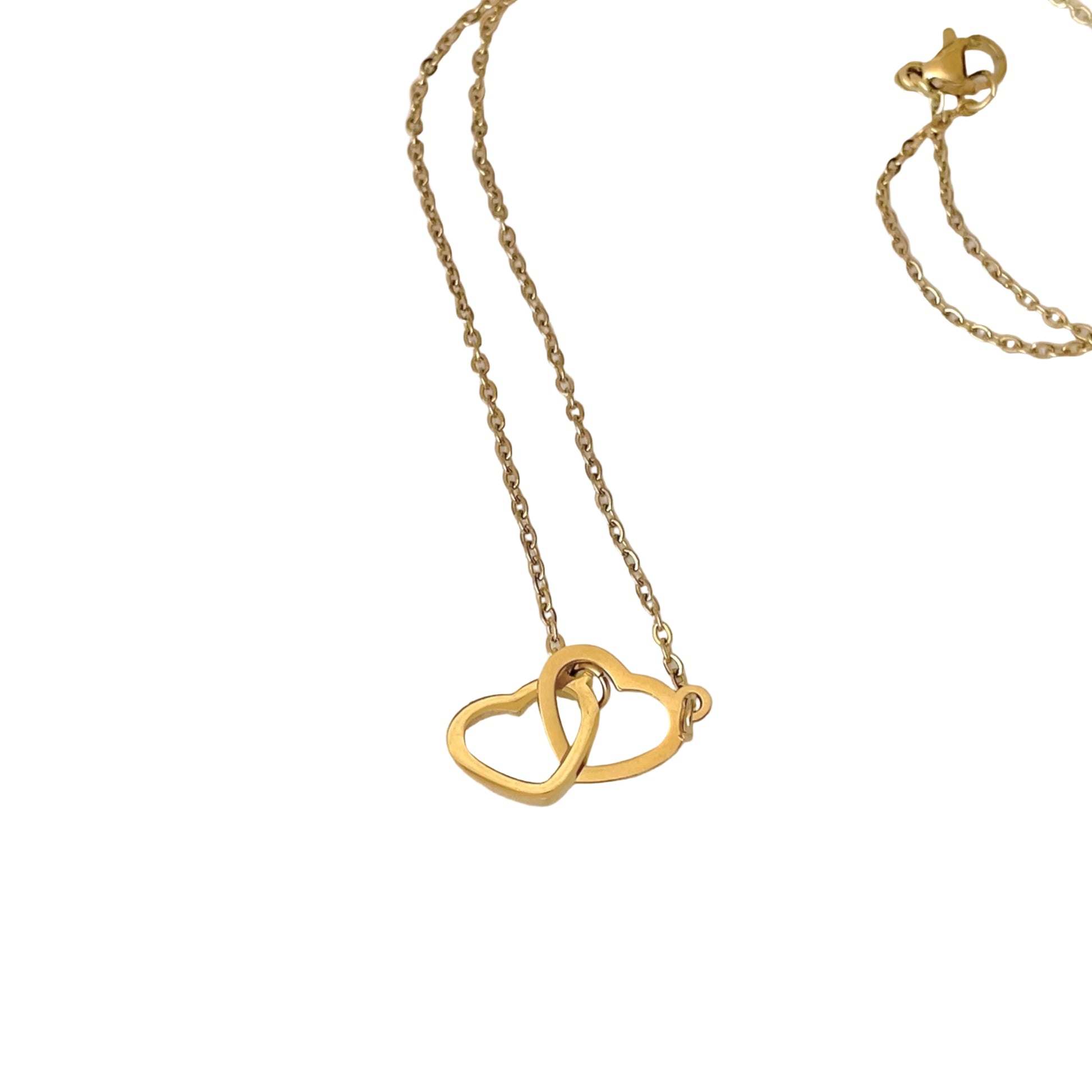Gold necklace with interlocking heart charm on a white background