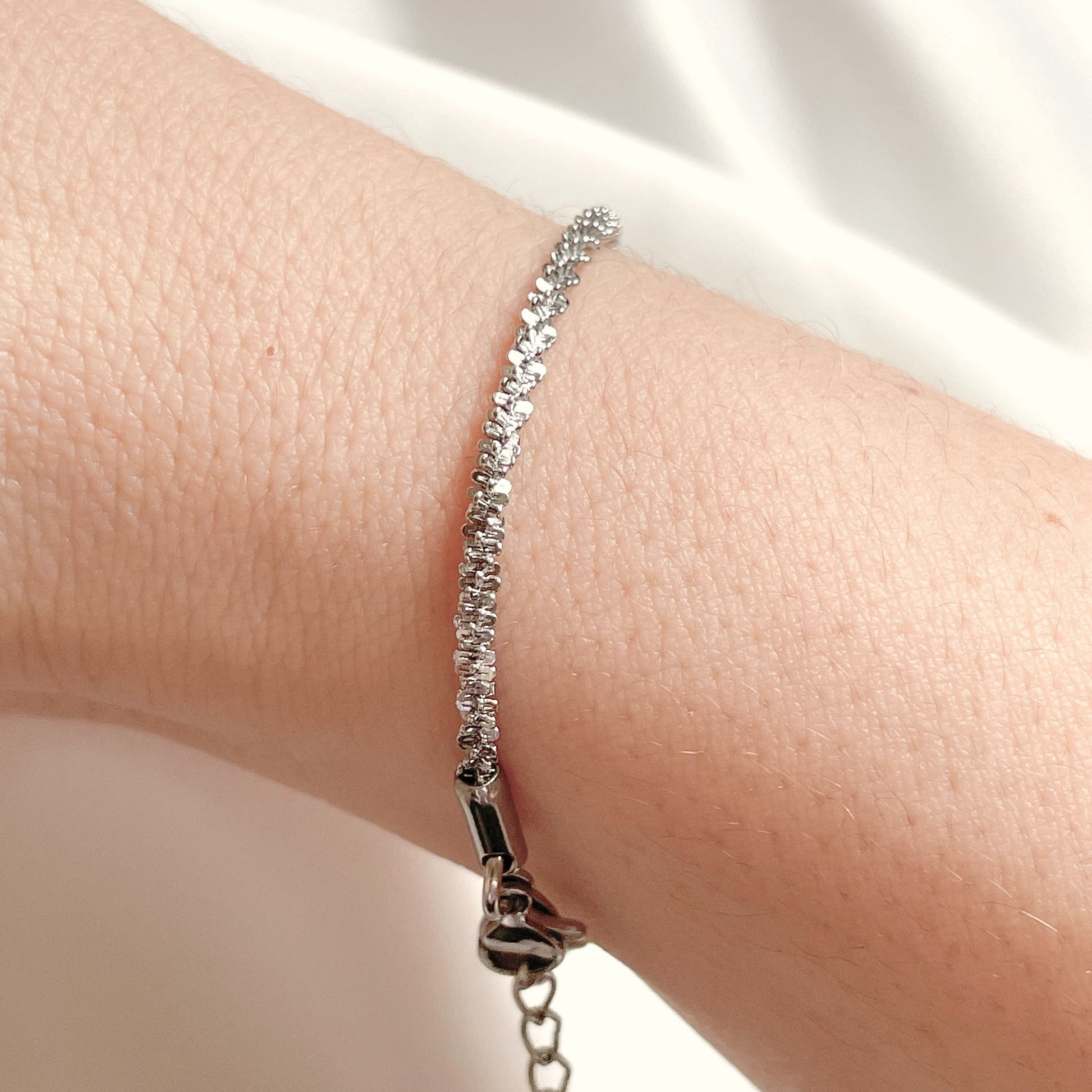 Side view of a wrist wearing silver rope chain bracelet