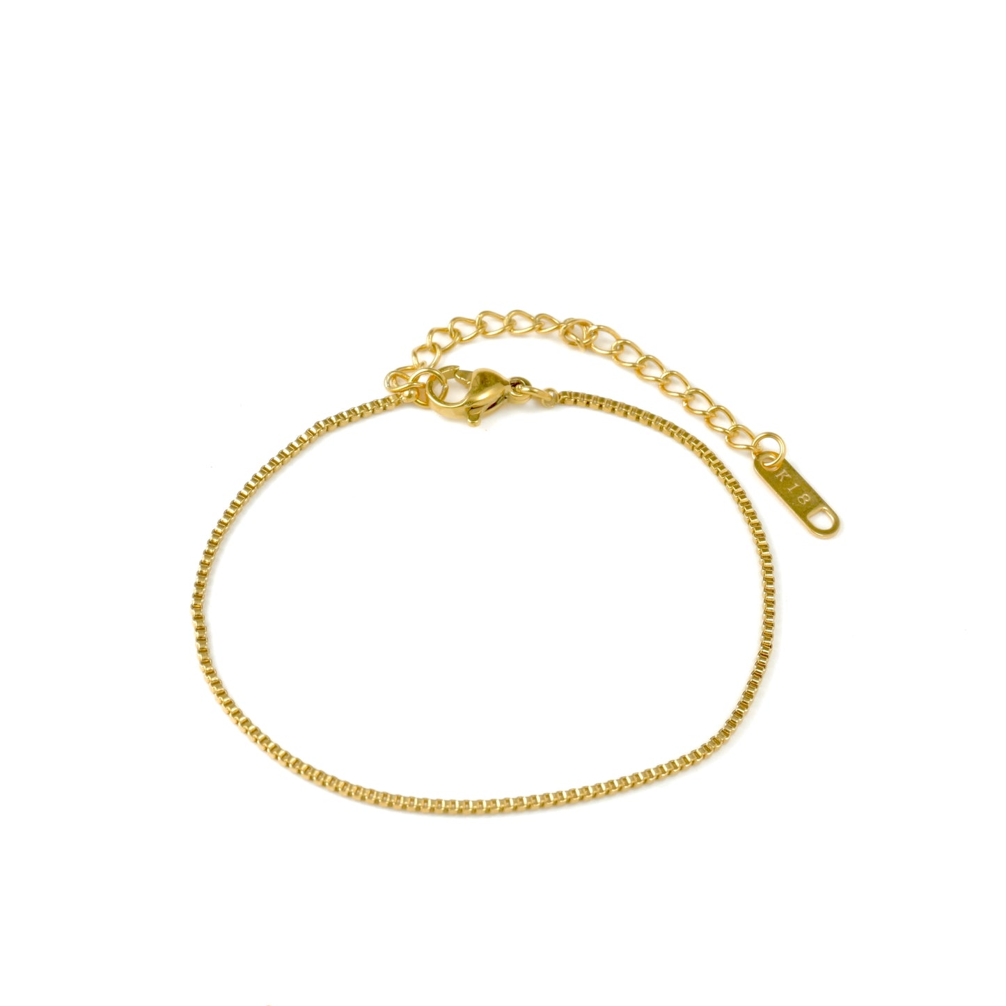 Top view of gold box chain bracelet  with a lobster claw clasp, extender and K18 plating hallmark tag on a white background