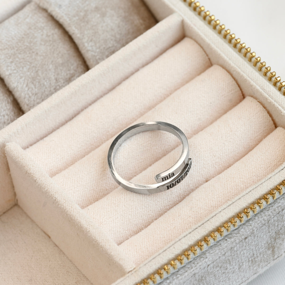 Thin silver bypass ring with engraved text in a jewelry box