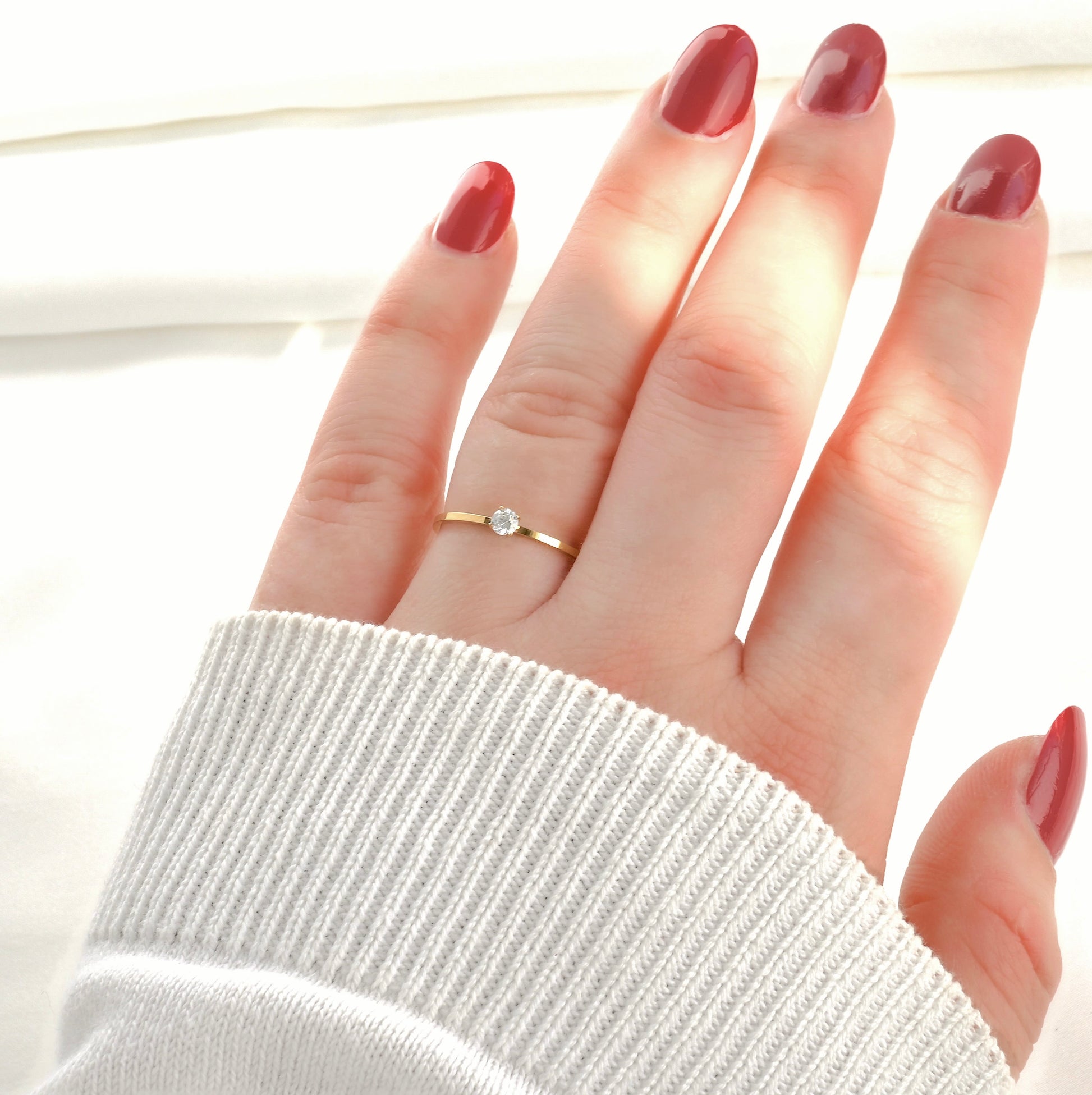 Hand wearing a gold CZ ring on a white background