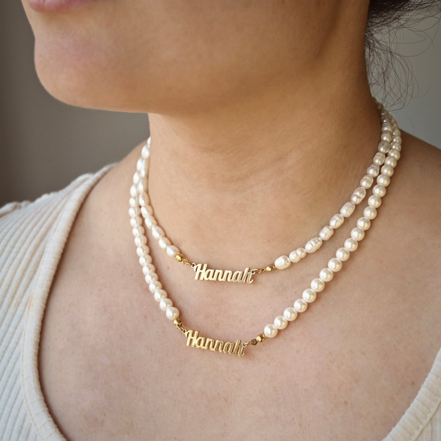 Person wearing a 'Hannah' necklace with freshwater and shell pearls showing the difference between two pearl types.