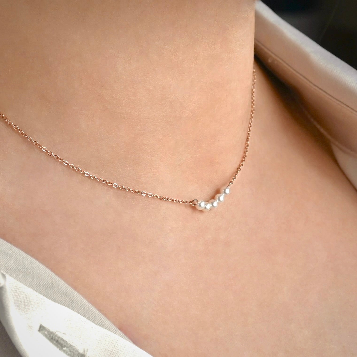 Rose gold necklace with pearls on a person's neck