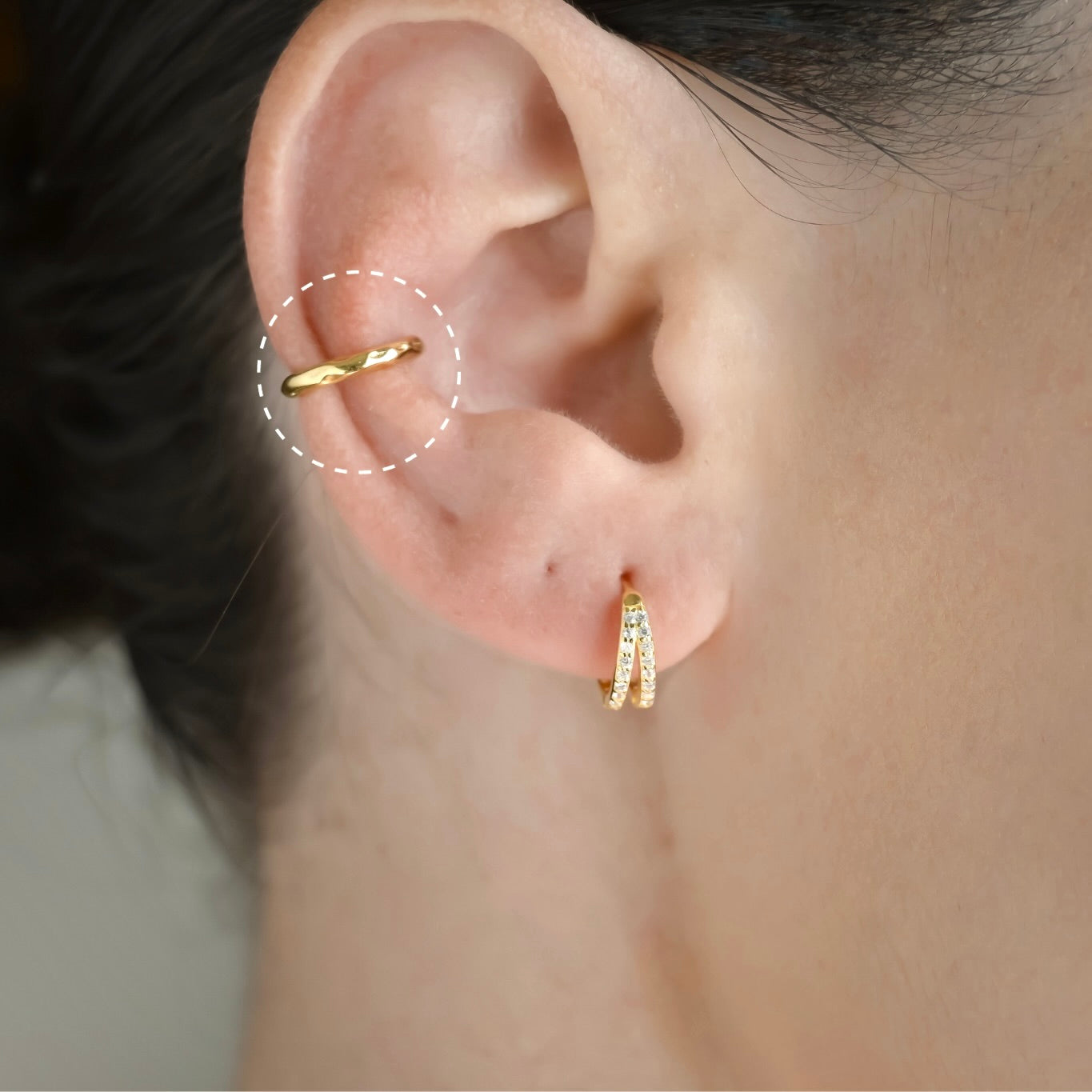 Close-up of an ear wearing hammered gold ear cuff stacked with a double pave cz huggie earrings