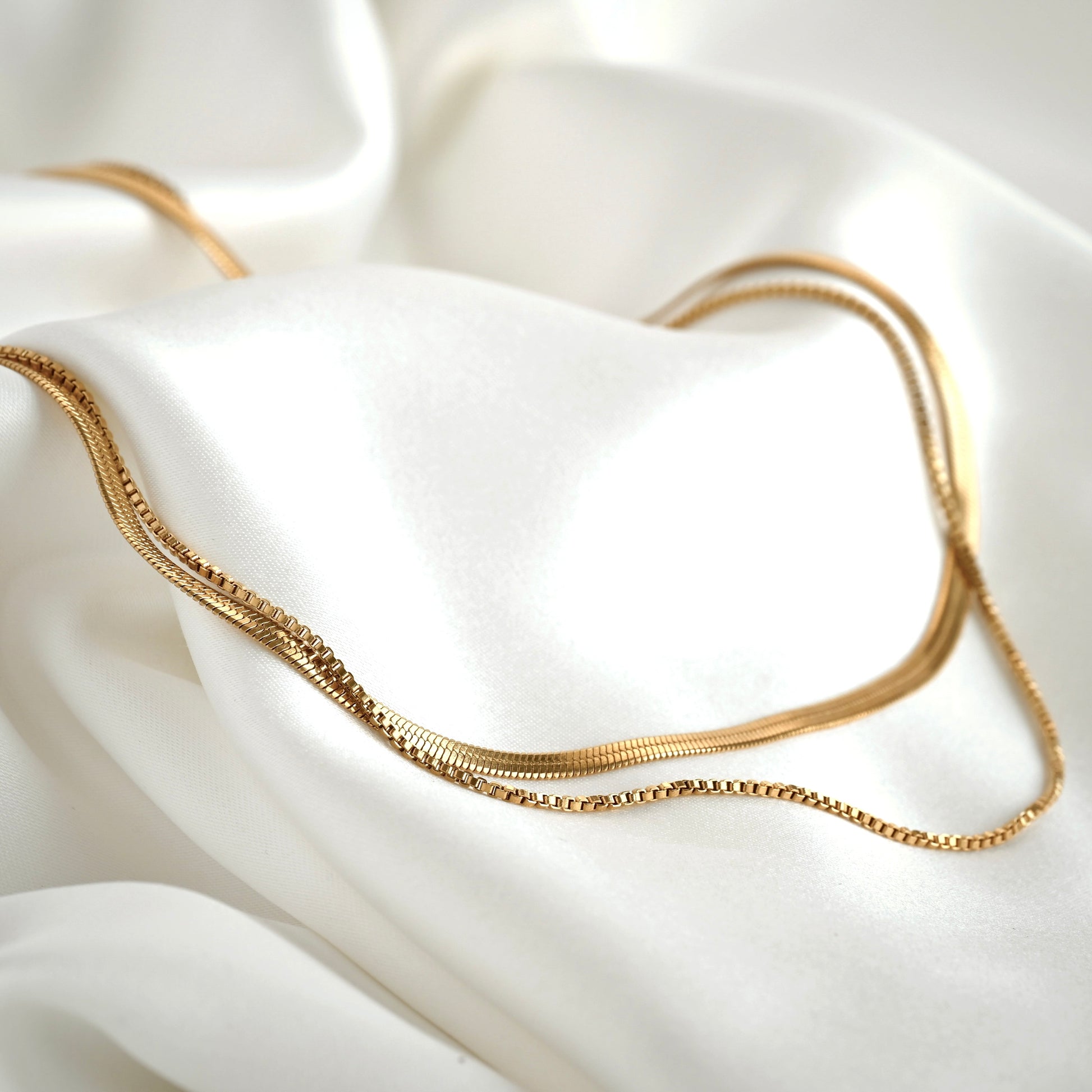 Gold chain necklace set on a white fabric background
