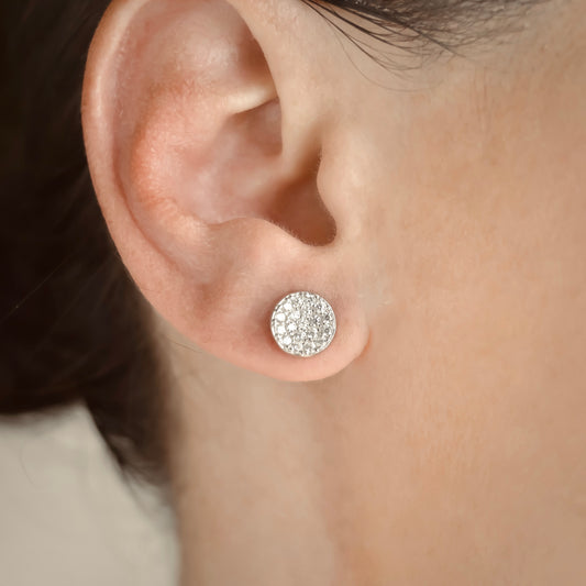 Close-up of an ear wearing a sparkling silver disc earring.