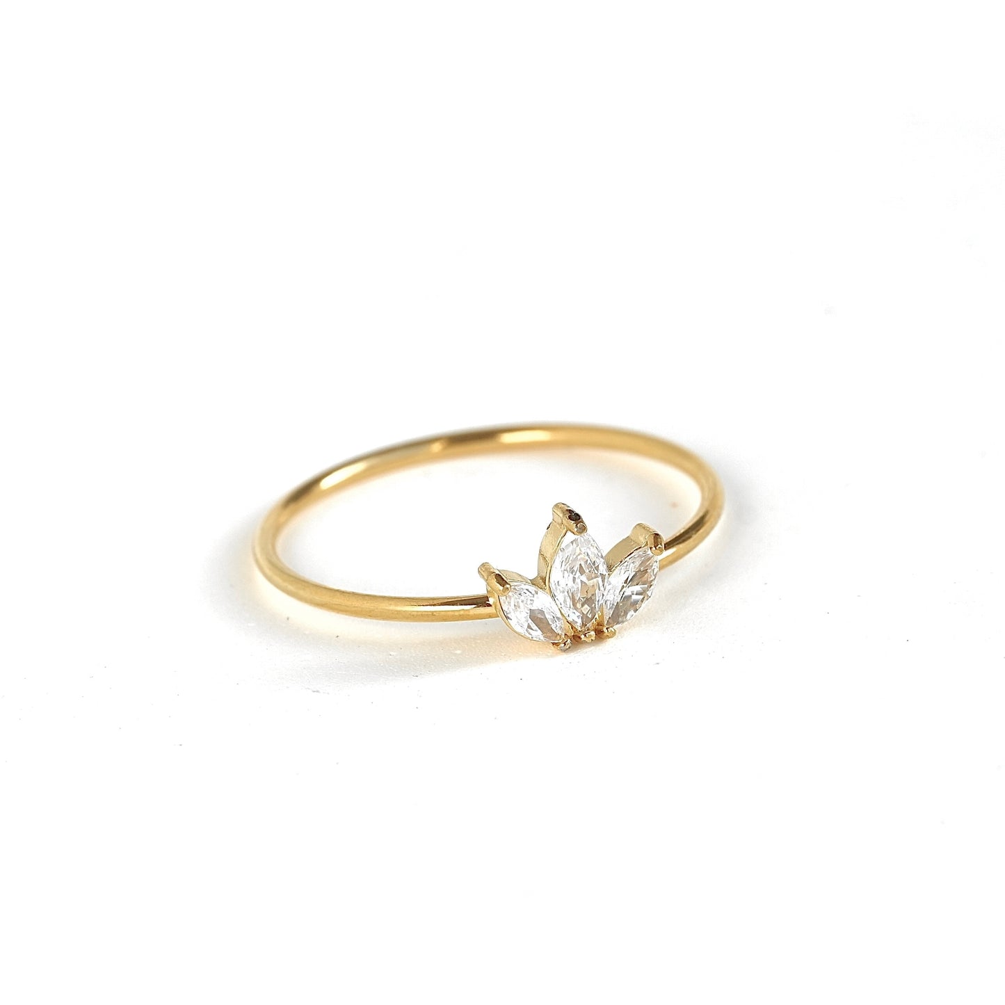 A delicate yellow gold ring featuring a marquise-cut clear gemstone cluster setting, photographed on a seamless white background.