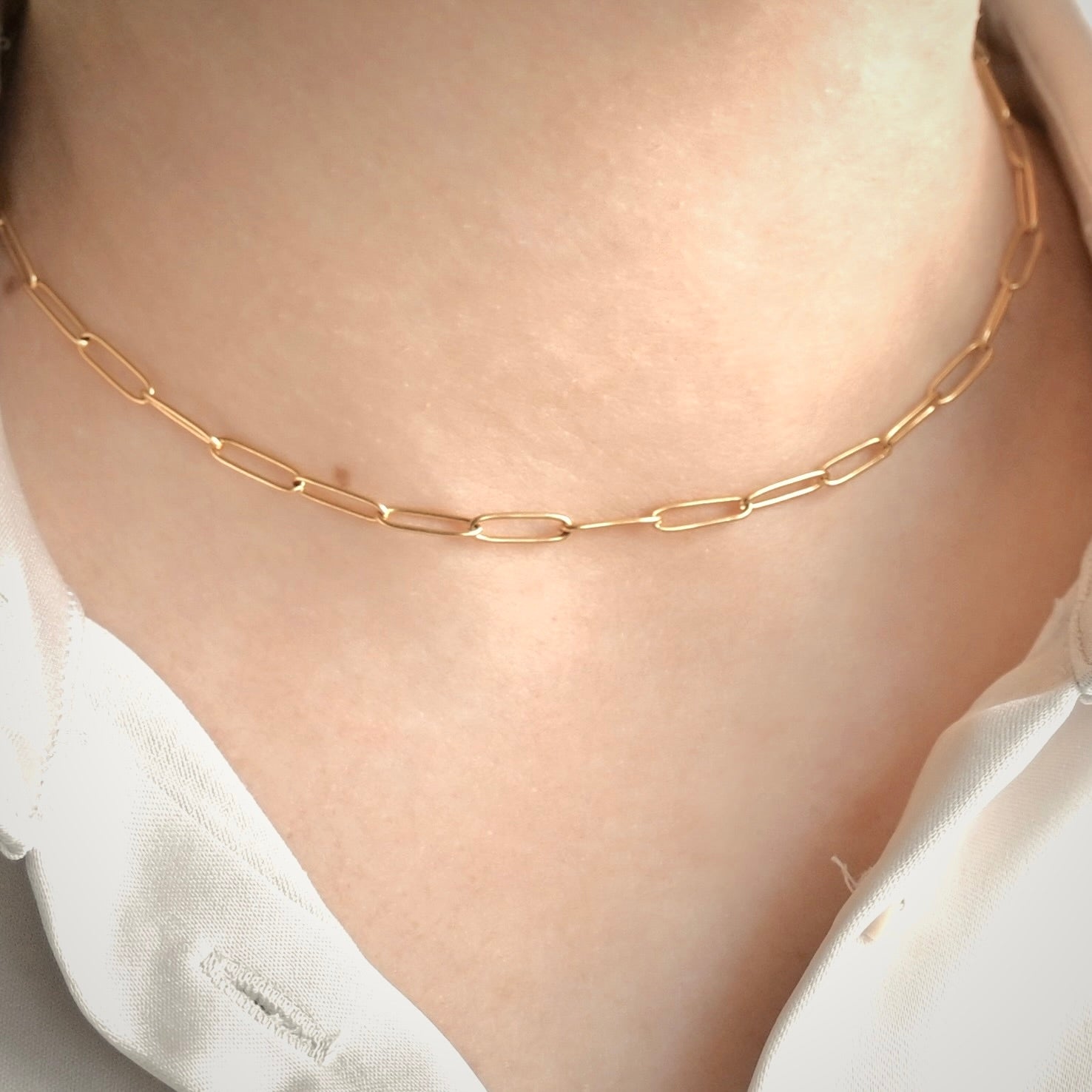 Front view of airy gold  paperclip chain necklace on a person with a white blouse