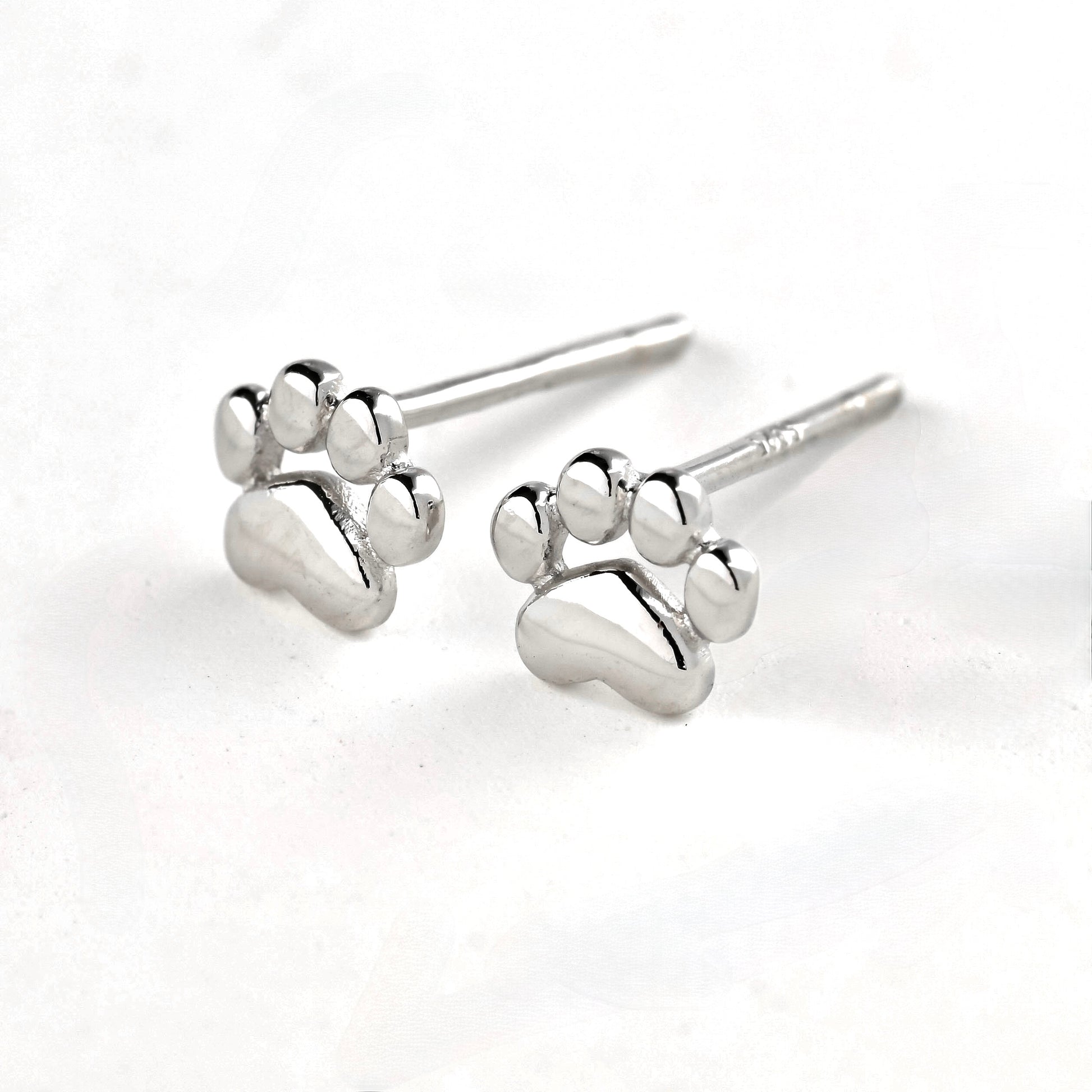 Solid silver paw stud earrings on a white background
