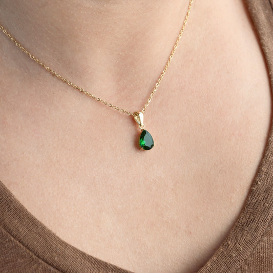 Gold may birthstone pendant on a person's neck.