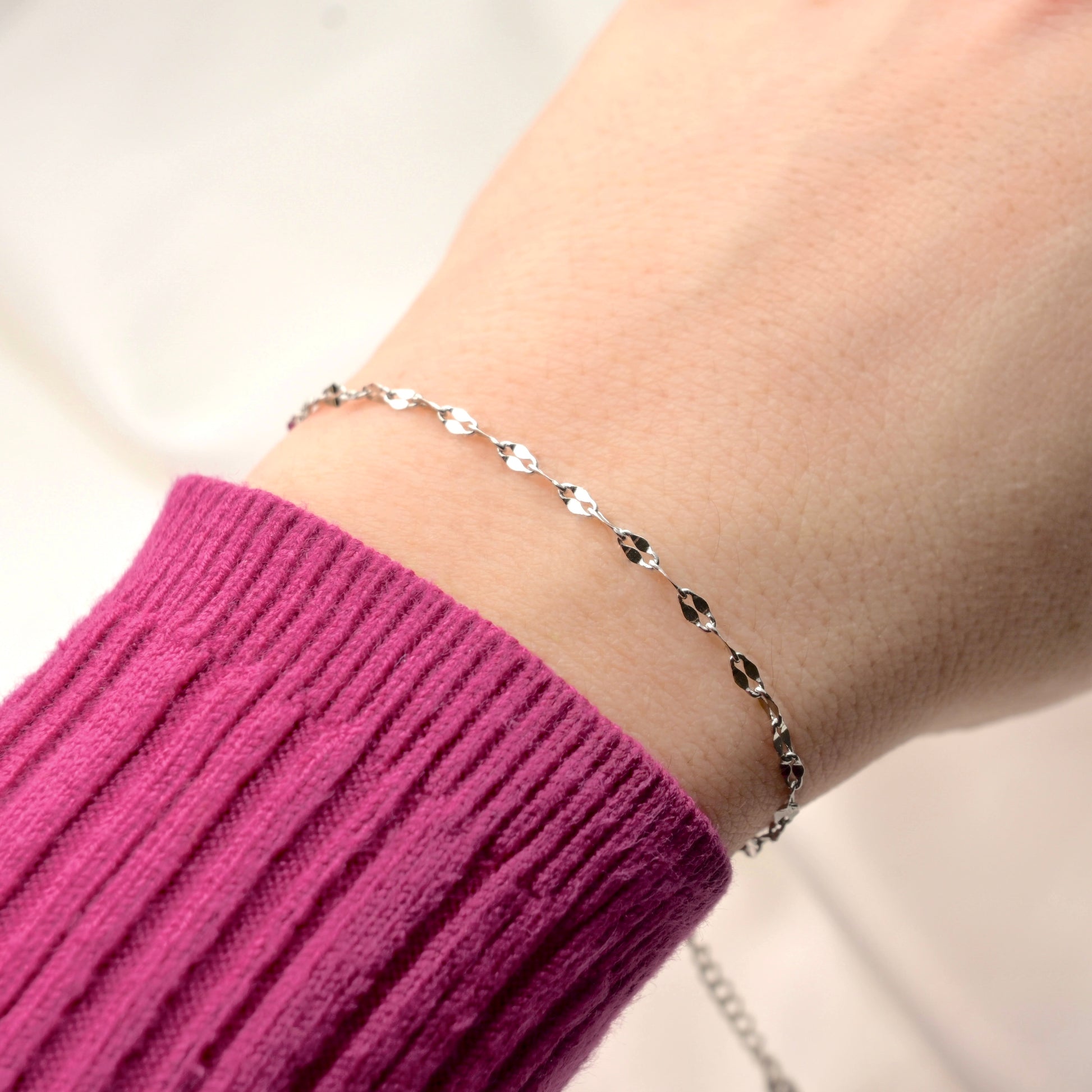 Silver sequin bracelet on a wrist with a blurred background